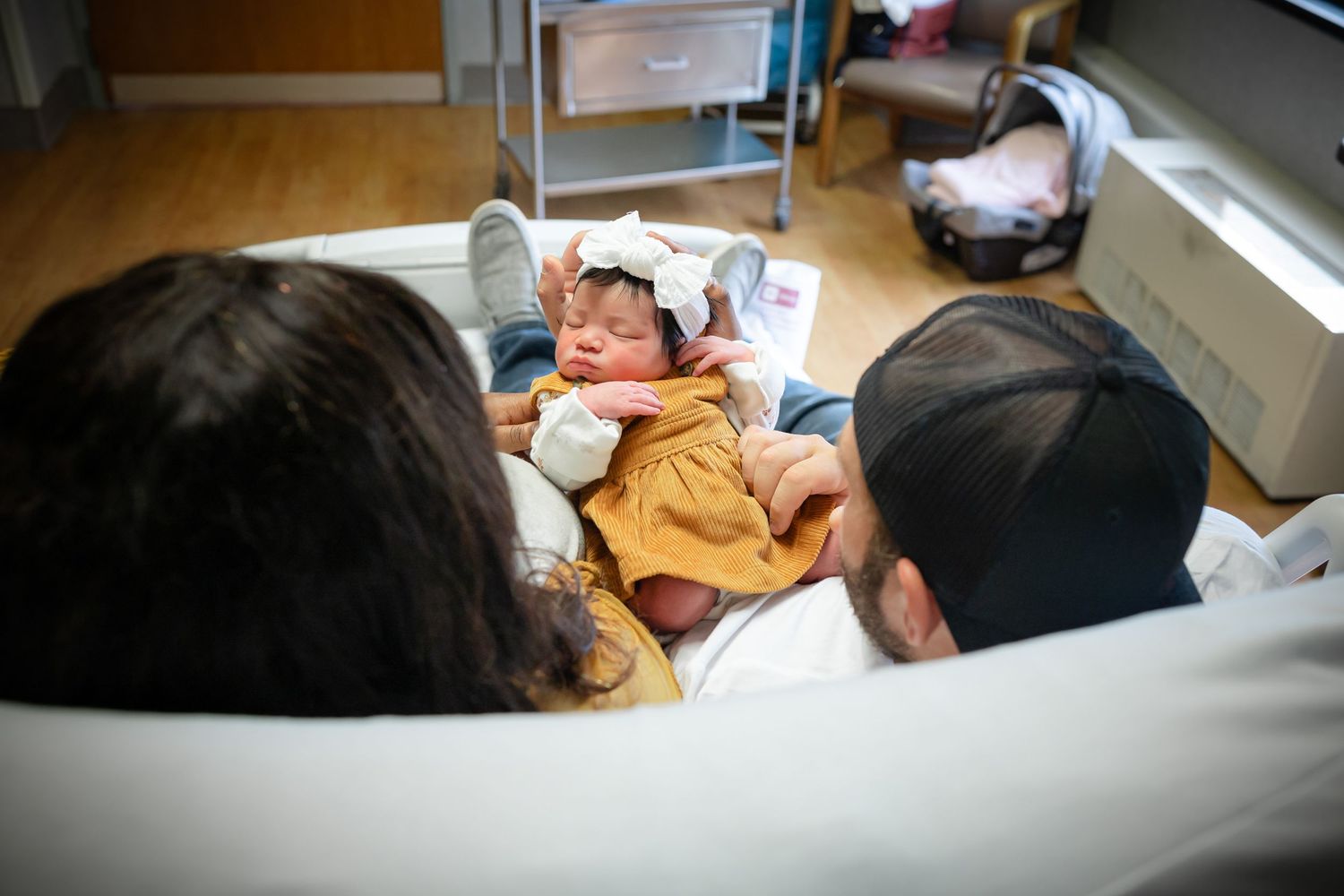 Newborn baby sleeping peacefully wrapped in a mustard yellow blanket.