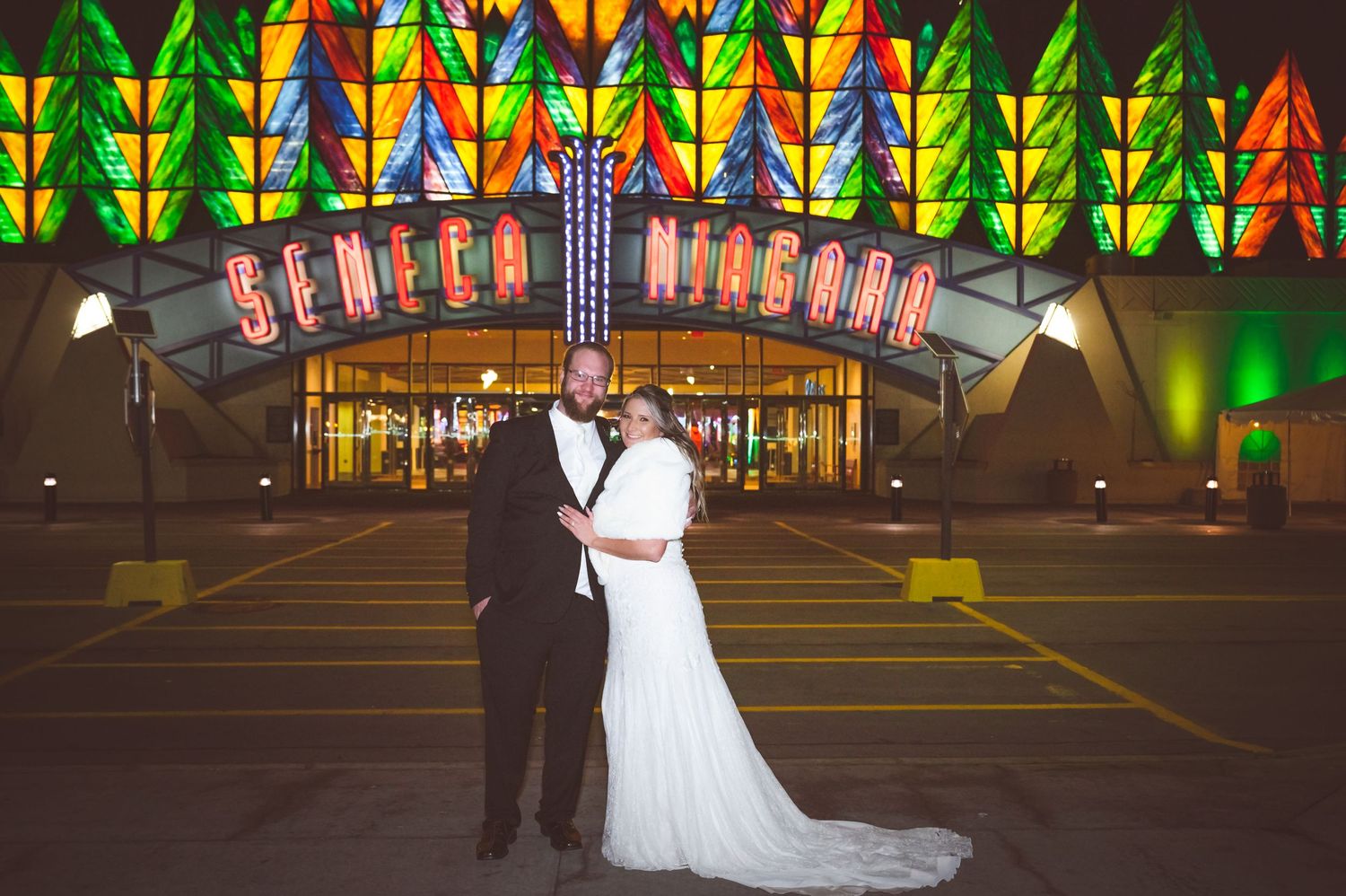 A nighttime wedding photo in front of the illuminated Seattle Museum with colorful geometric lighting patterns.