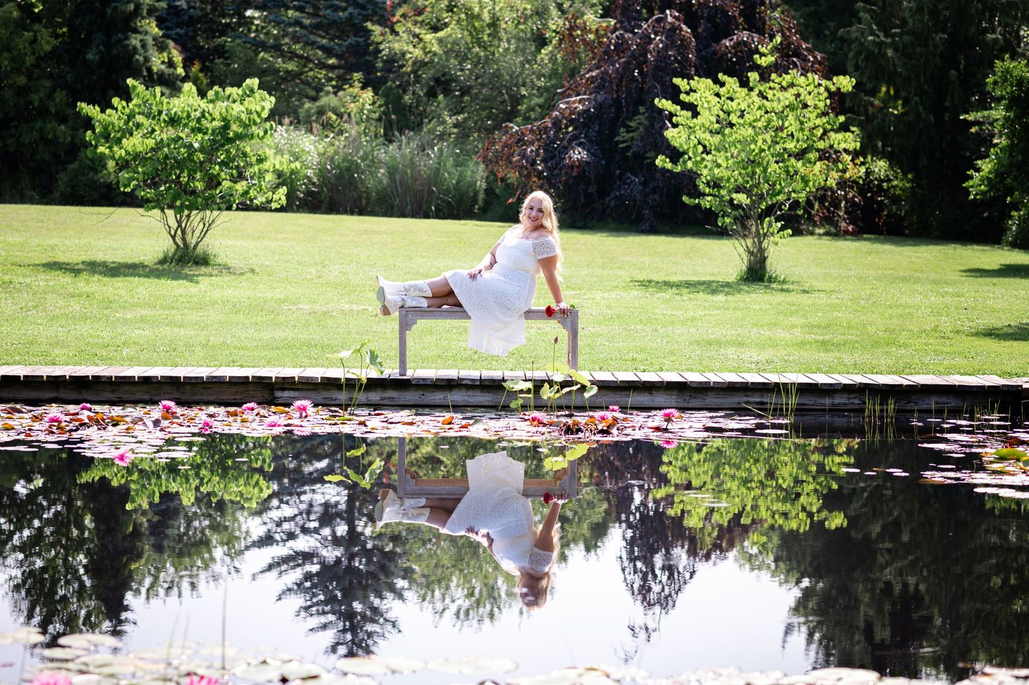 A reflection captured in a garden pond with greenery and lily pads.