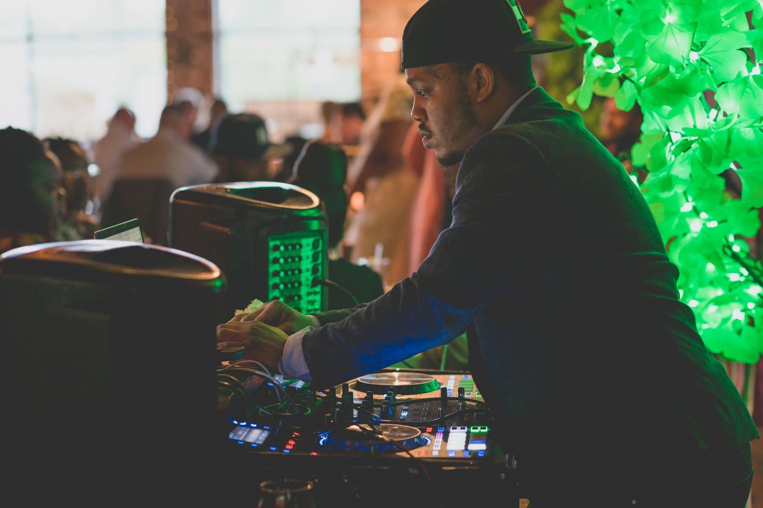A DJ performing at a wedding reception with green lighting effects in the background.