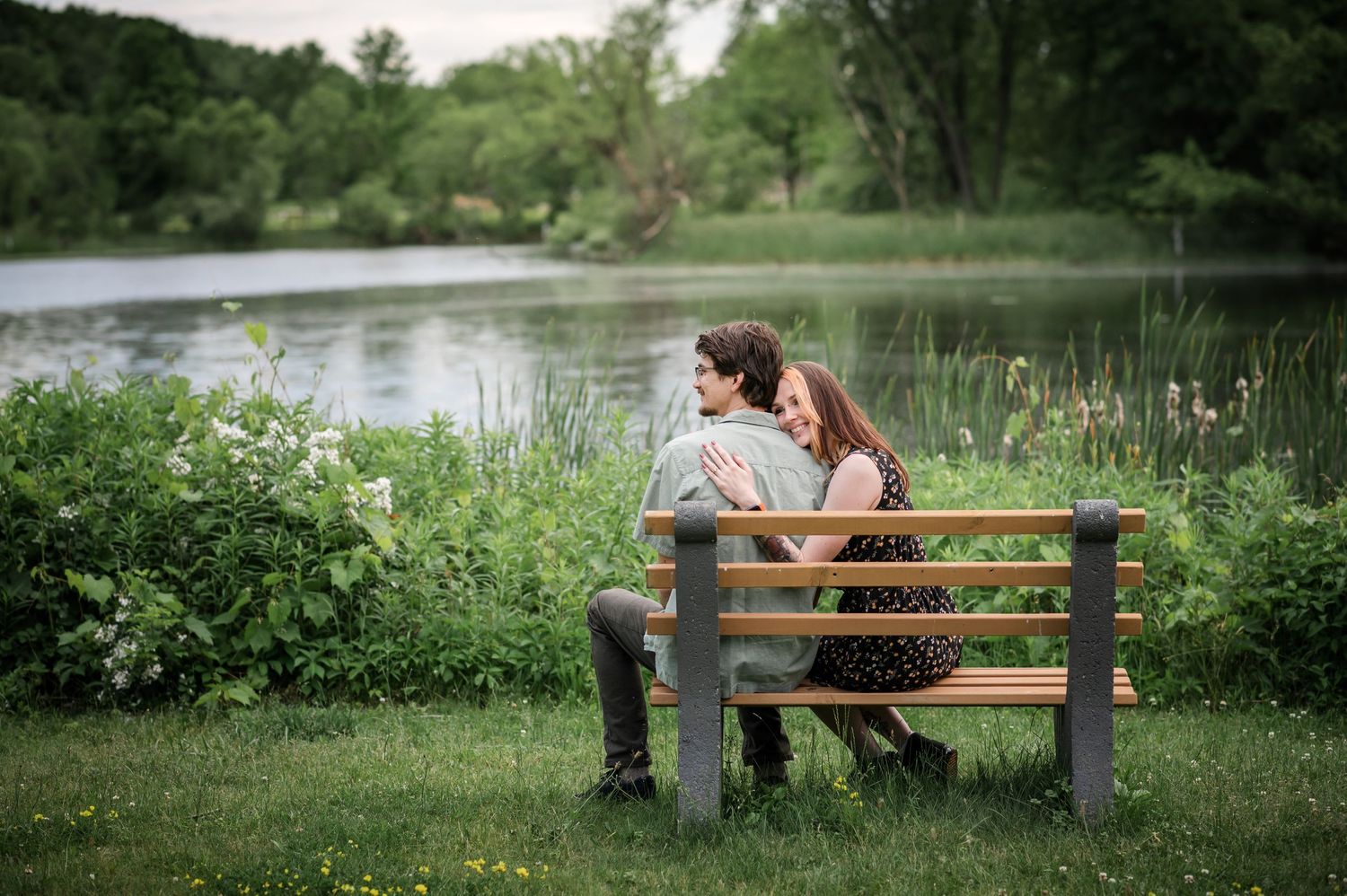 Romantic couple shares tender moment on park bench by serene lake.