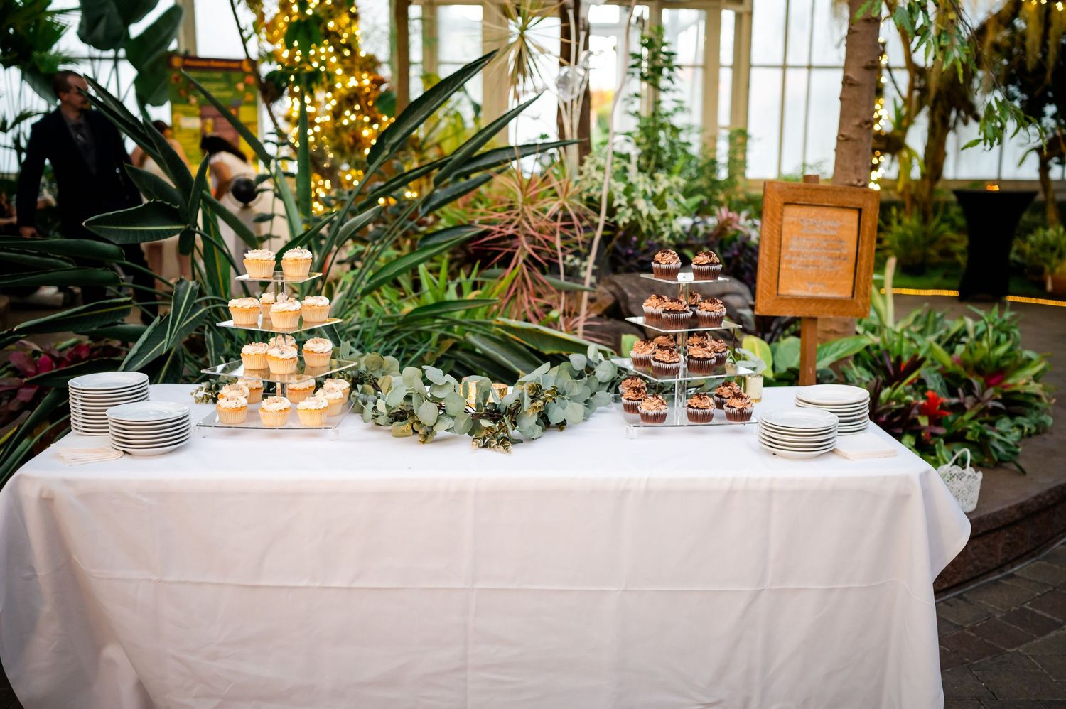 Elegant dessert table with cupcakes and treats decorated with botanical elements.