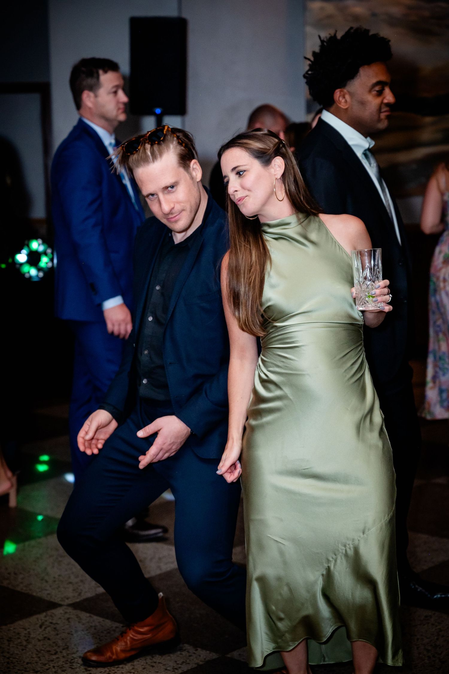 Wedding guests dancing at a reception with green lighting effects.