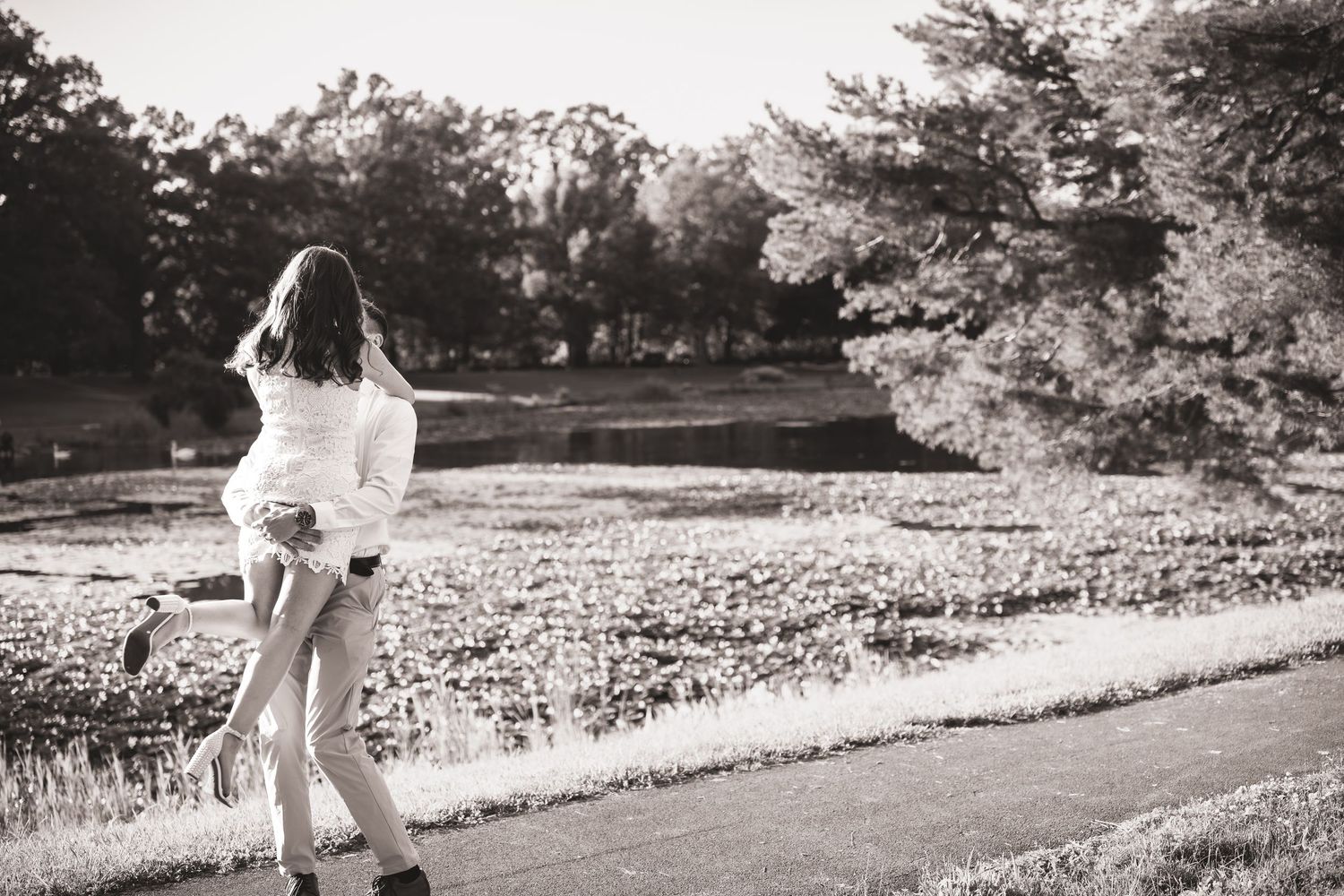 Couple embracing on a path in a lush park, black and white romantic outdoor photo.