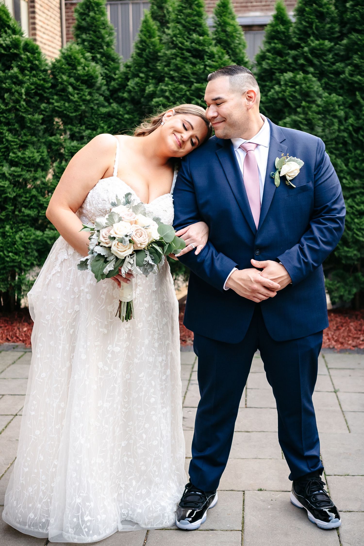 A joyful wedding moment captured against a backdrop of green shrubs.