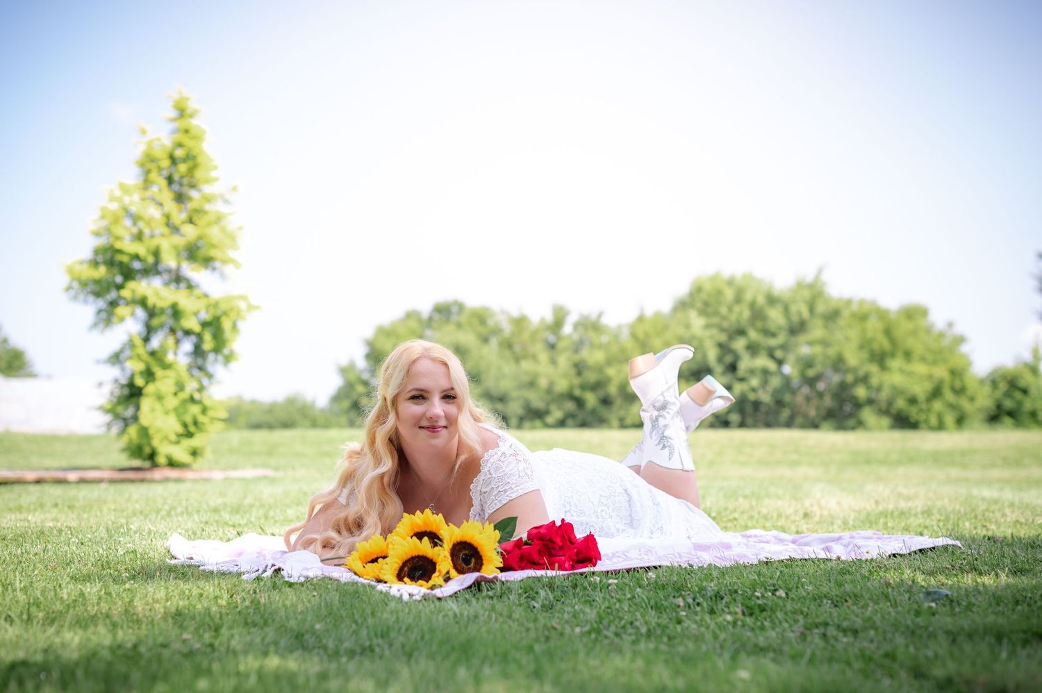 A summer portrait on grass with bright sunflowers and red flowers creating a cheerful scene.