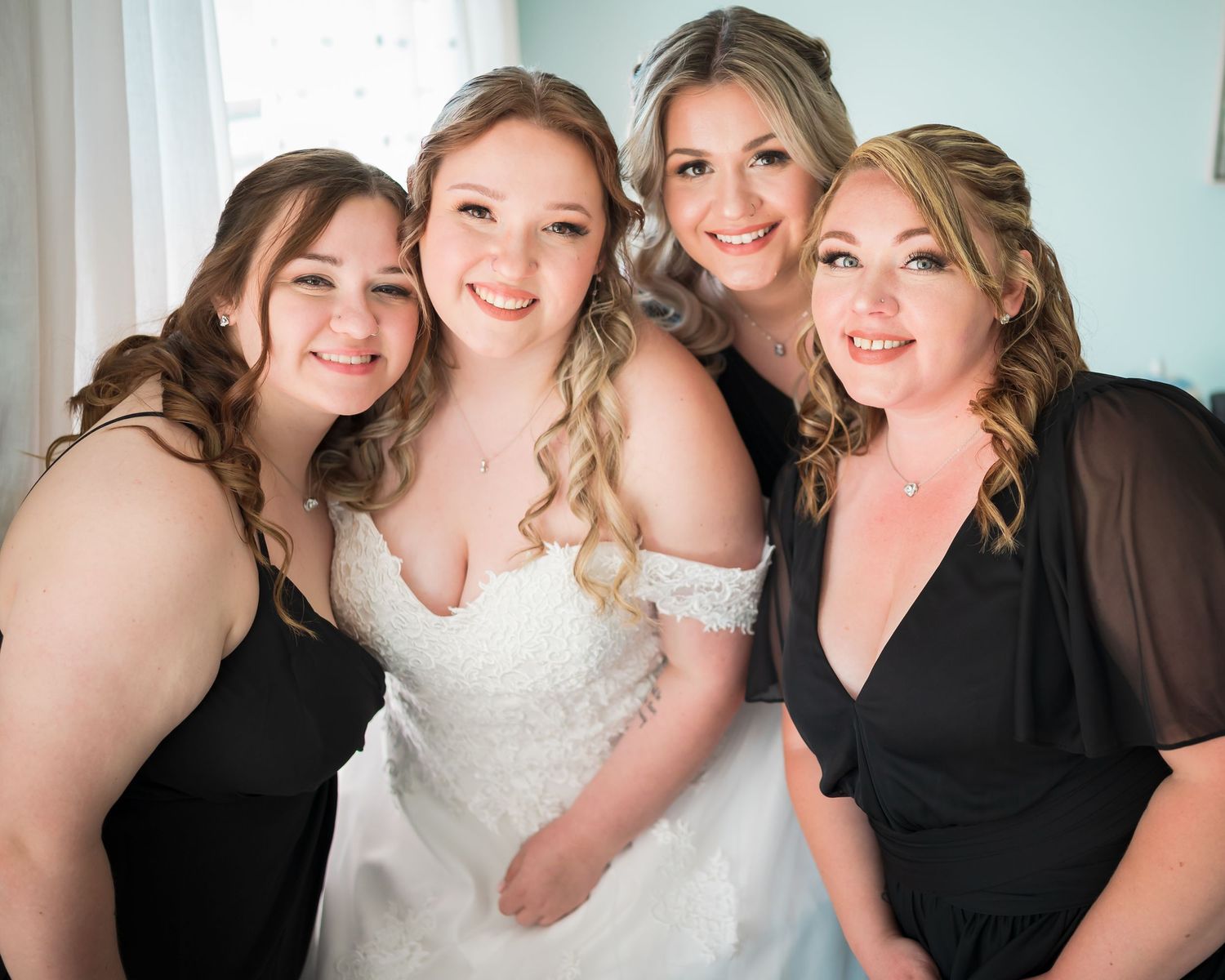 A bridal party poses together in coordinated black dresses and a white wedding gown.