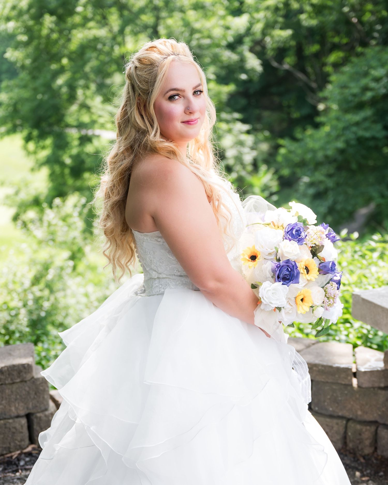 A bridal portrait on stone steps featuring a white ballgown and colorful spring bouquet.