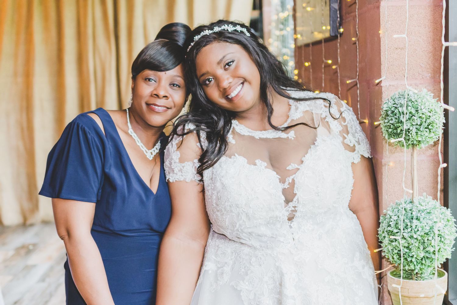 A wedding portrait showing a touching moment between the bride and woman in navy.