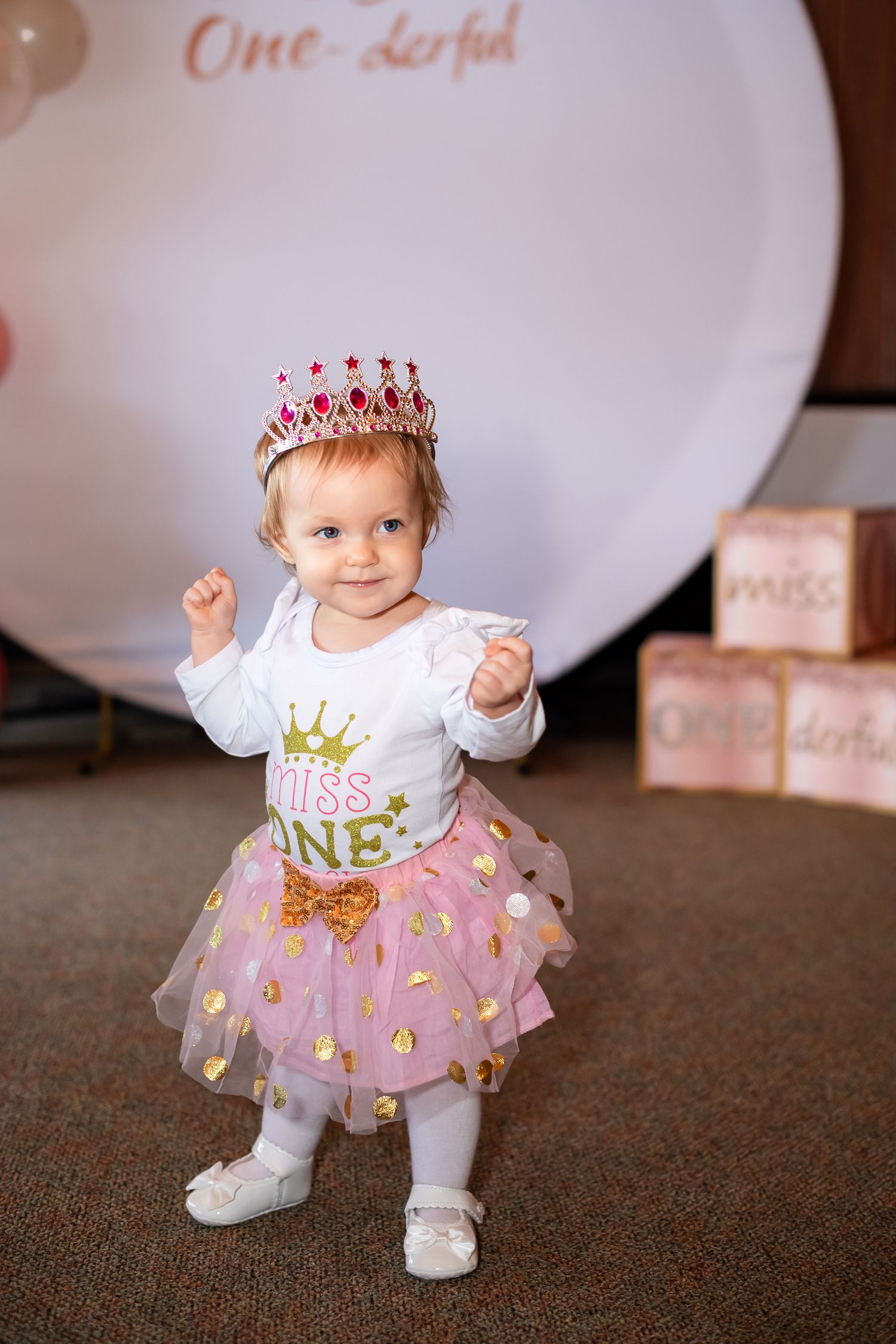 A small child wearing a pink tulle tutu, crown and white shirt poses in four sequential birthday celebration photos.