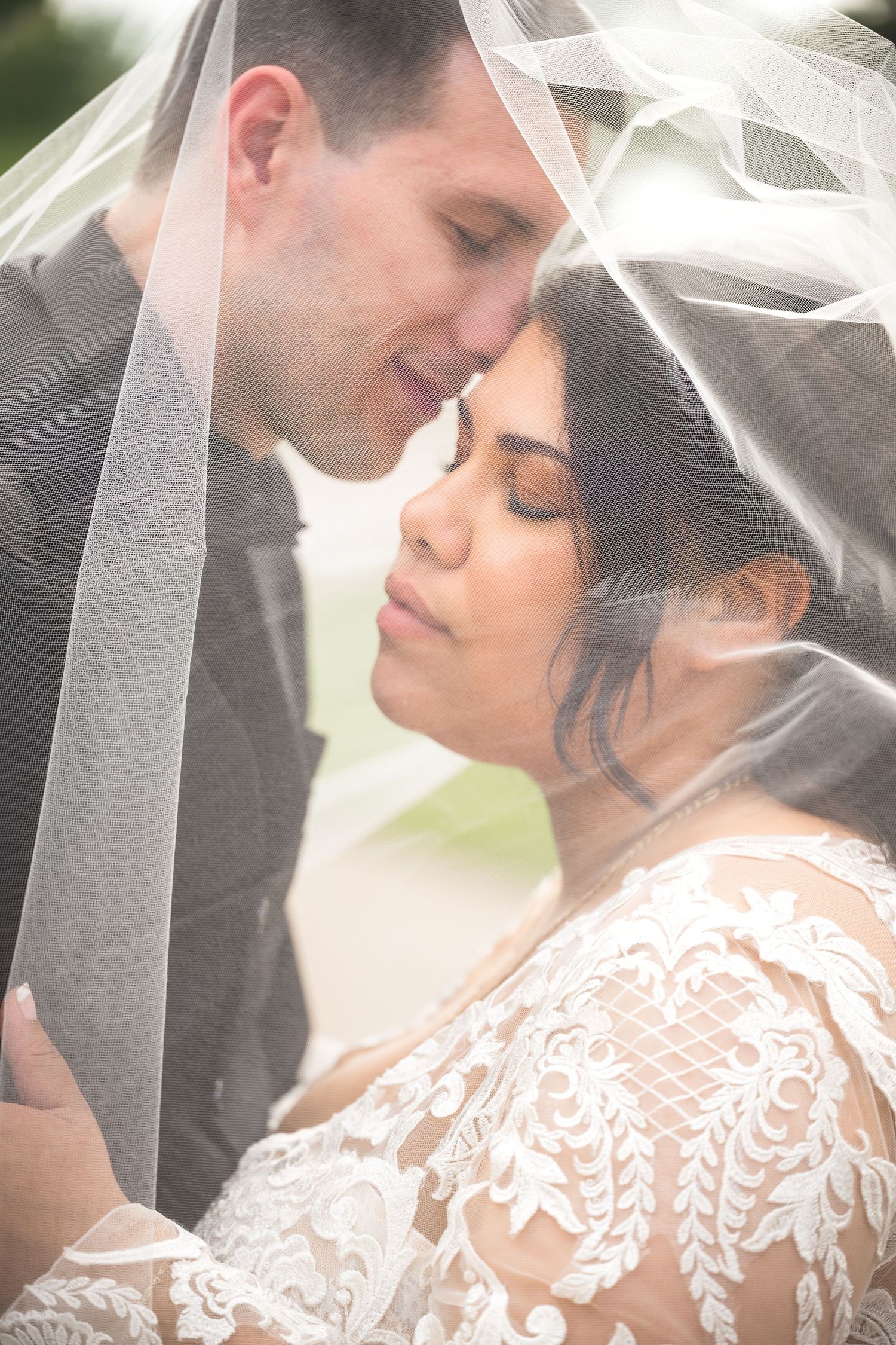 Romantic wedding photo with couple sharing an intimate moment under a delicate white veil.