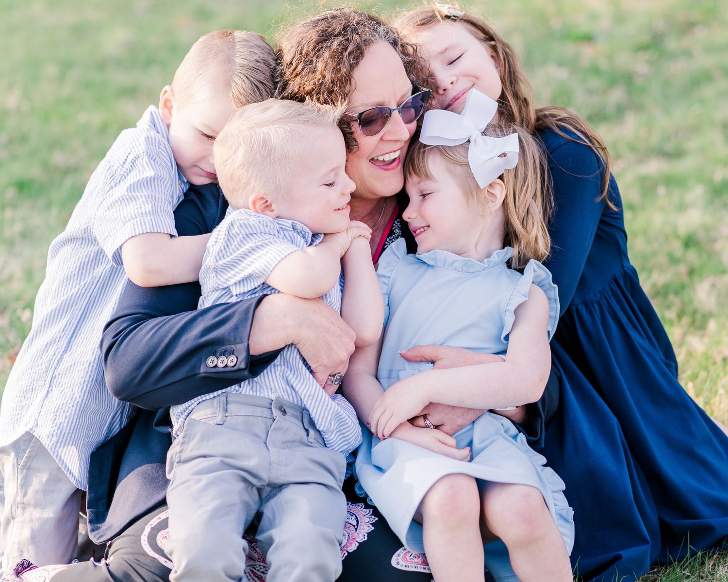 Family group hug outdoors with children in coordinated blue and white outfits.