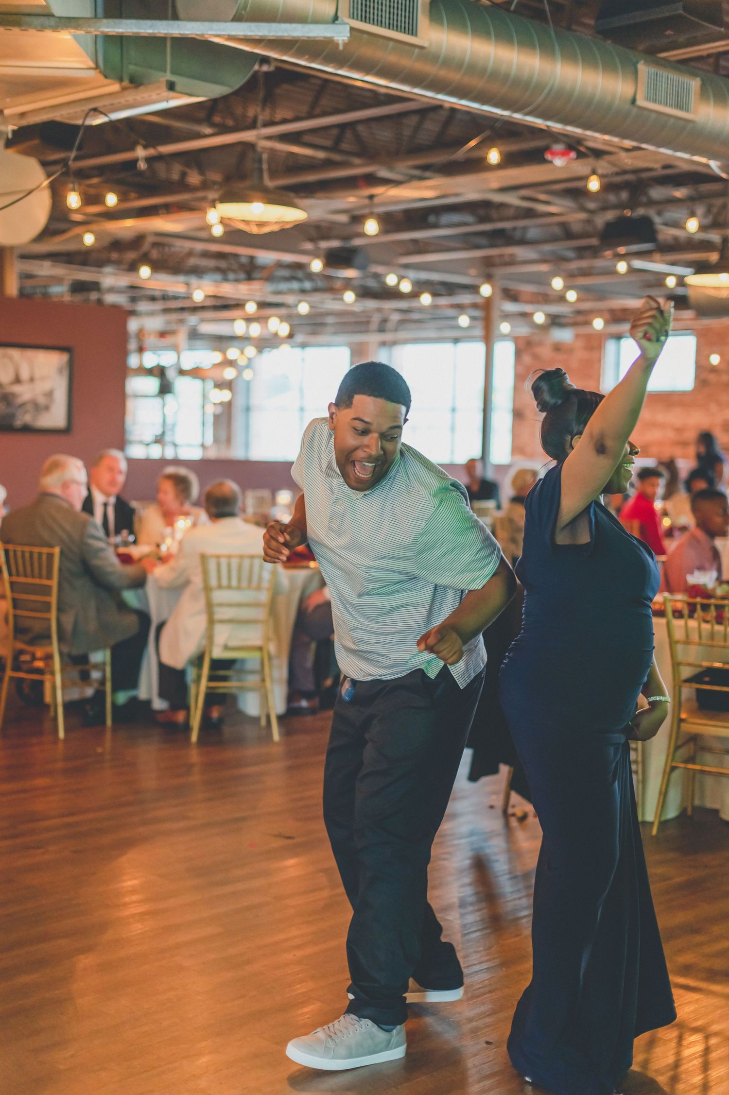 Guests dancing energetically on wooden dance floor at reception venue.