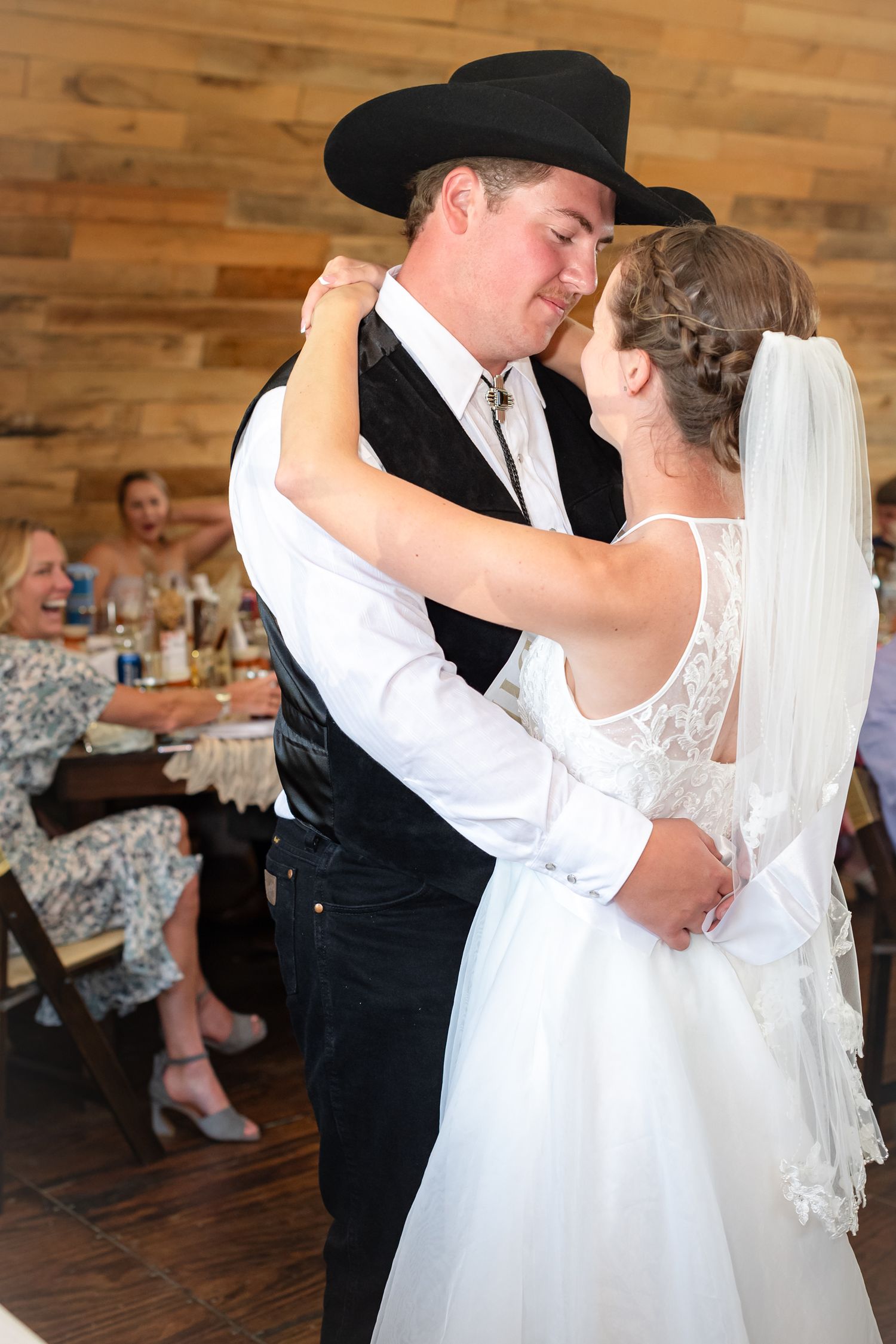 Romantic first dance between couple in rustic venue with wooden walls.