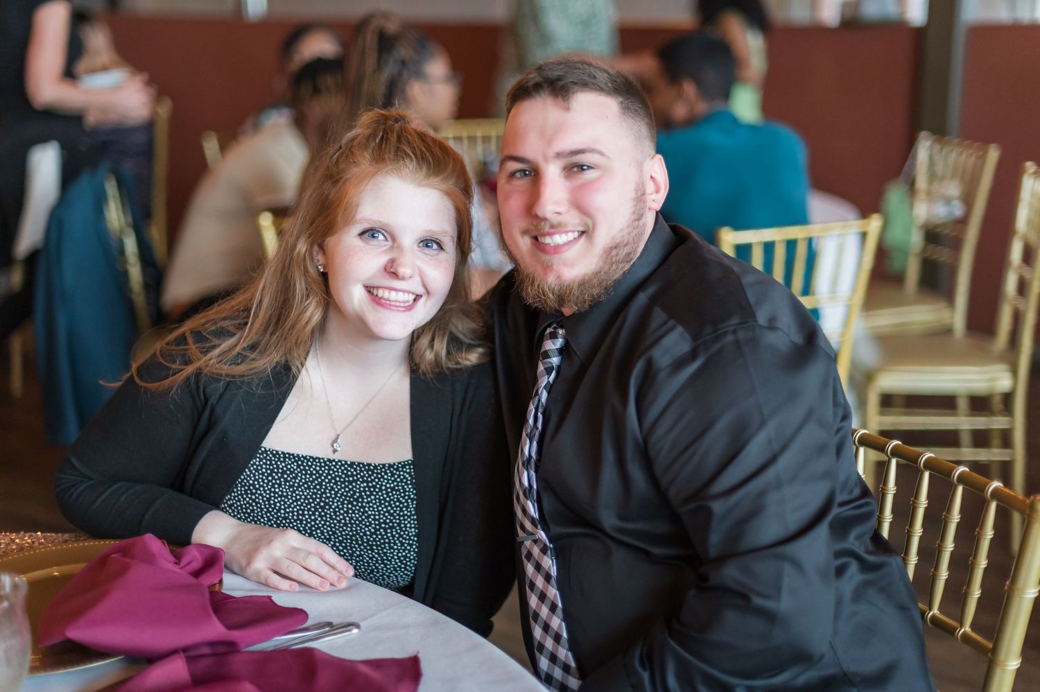 Couple smiling together at decorated table during indoor celebration event.