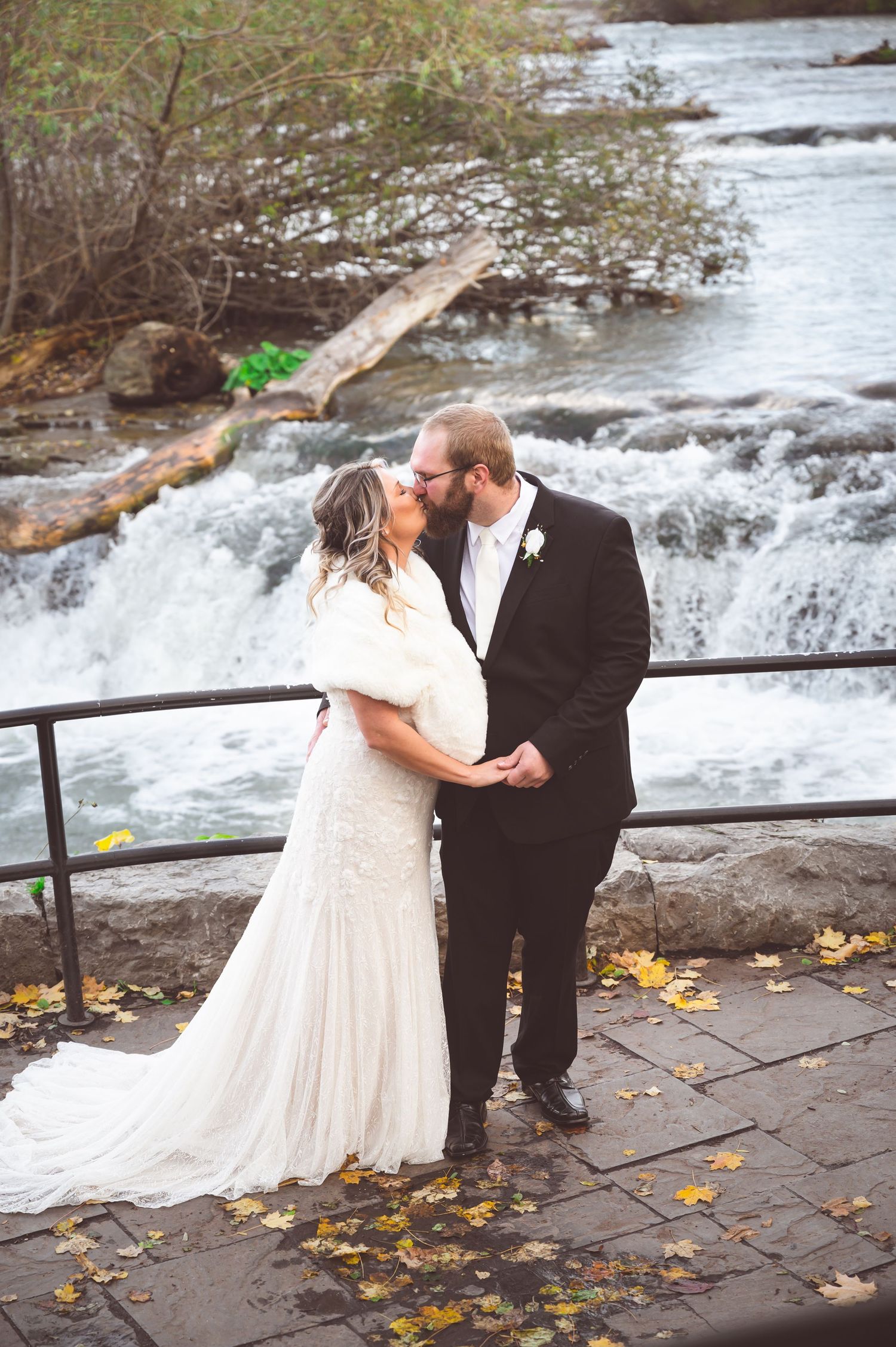 A tender wedding moment captured against the backdrop of rushing waterfalls and fall foliage.