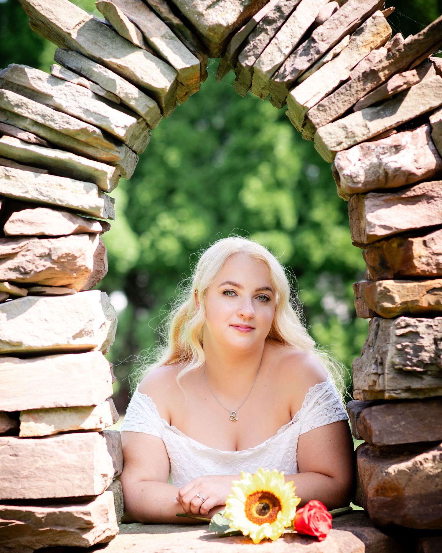 Romantic portrait through rustic stone archway with sunflower and rose decor.