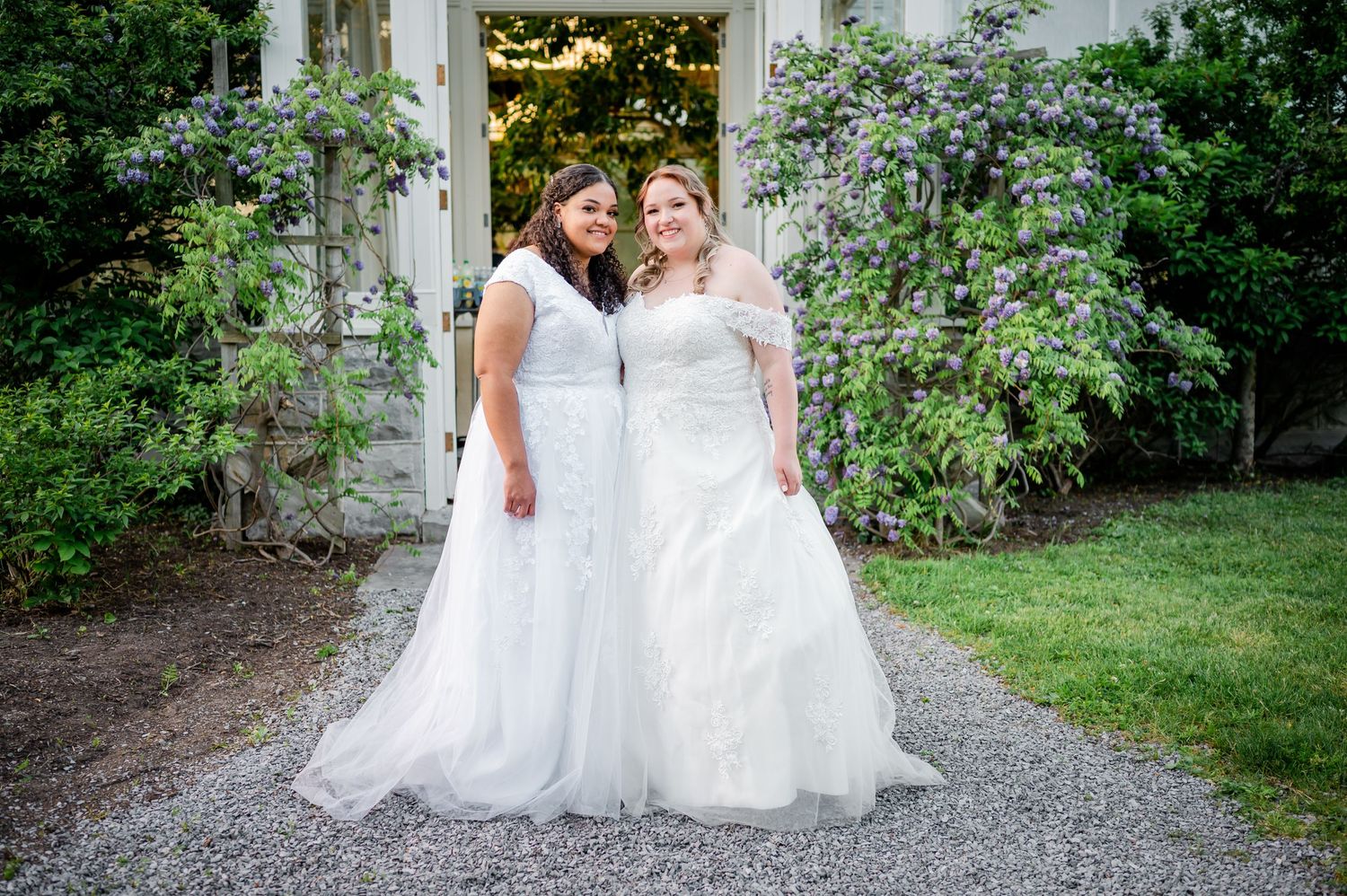 Wedding couple shares romantic moment in front of floral-covered garden arbor.