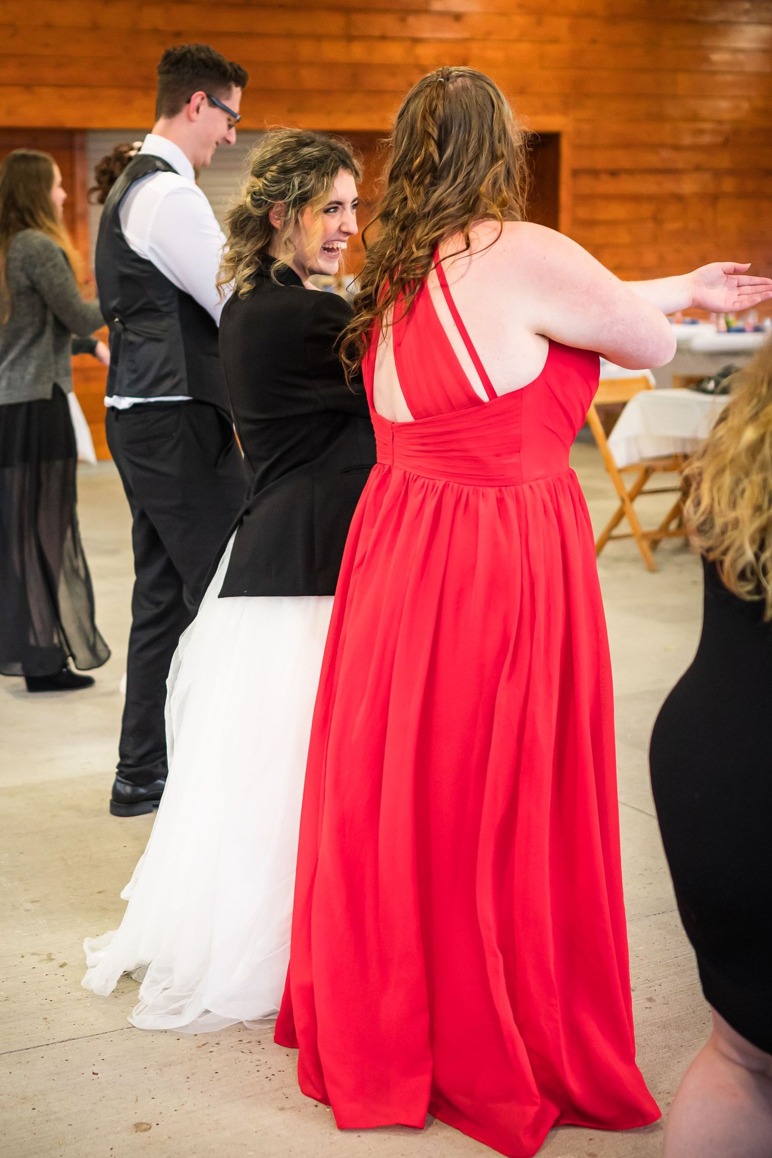 Wedding guests dancing and celebrating at rustic indoor venue with wooden walls.