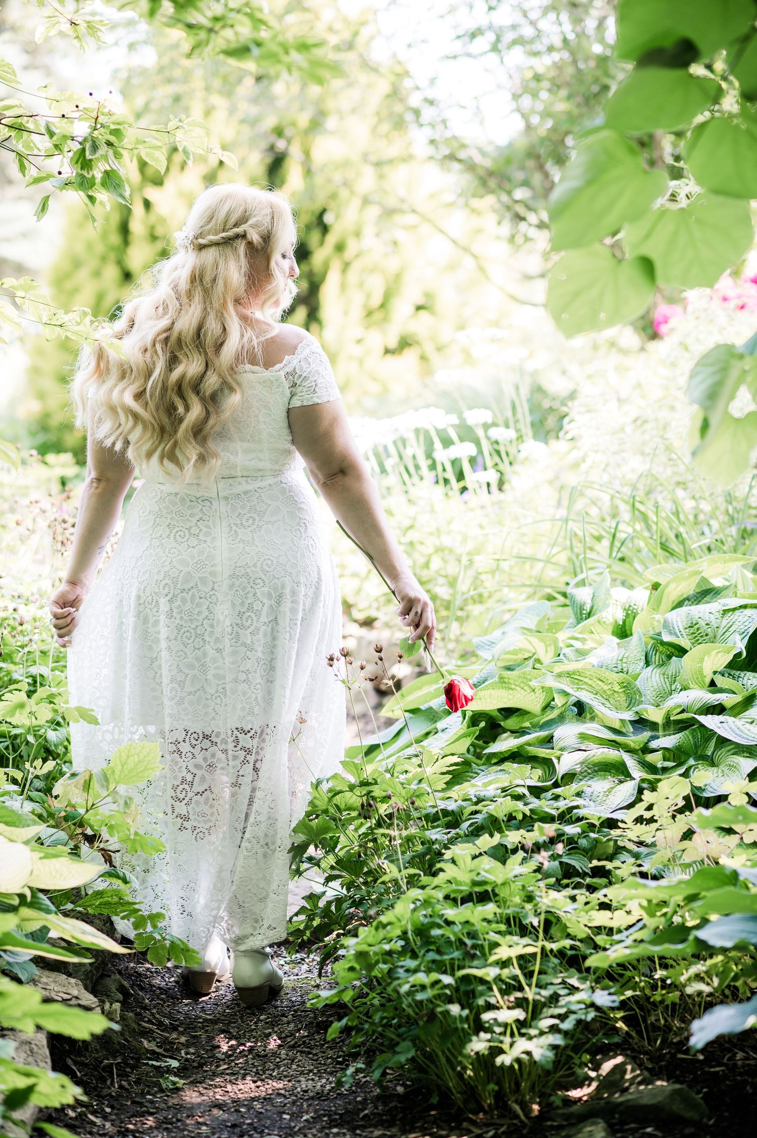 A ethereal garden scene with a white lace dress flowing through green foliage.