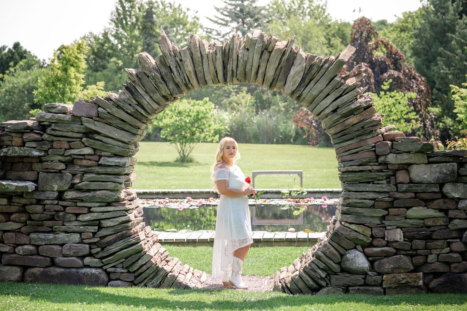 A striking stone arch creates a circular frame in a sunny garden setting.