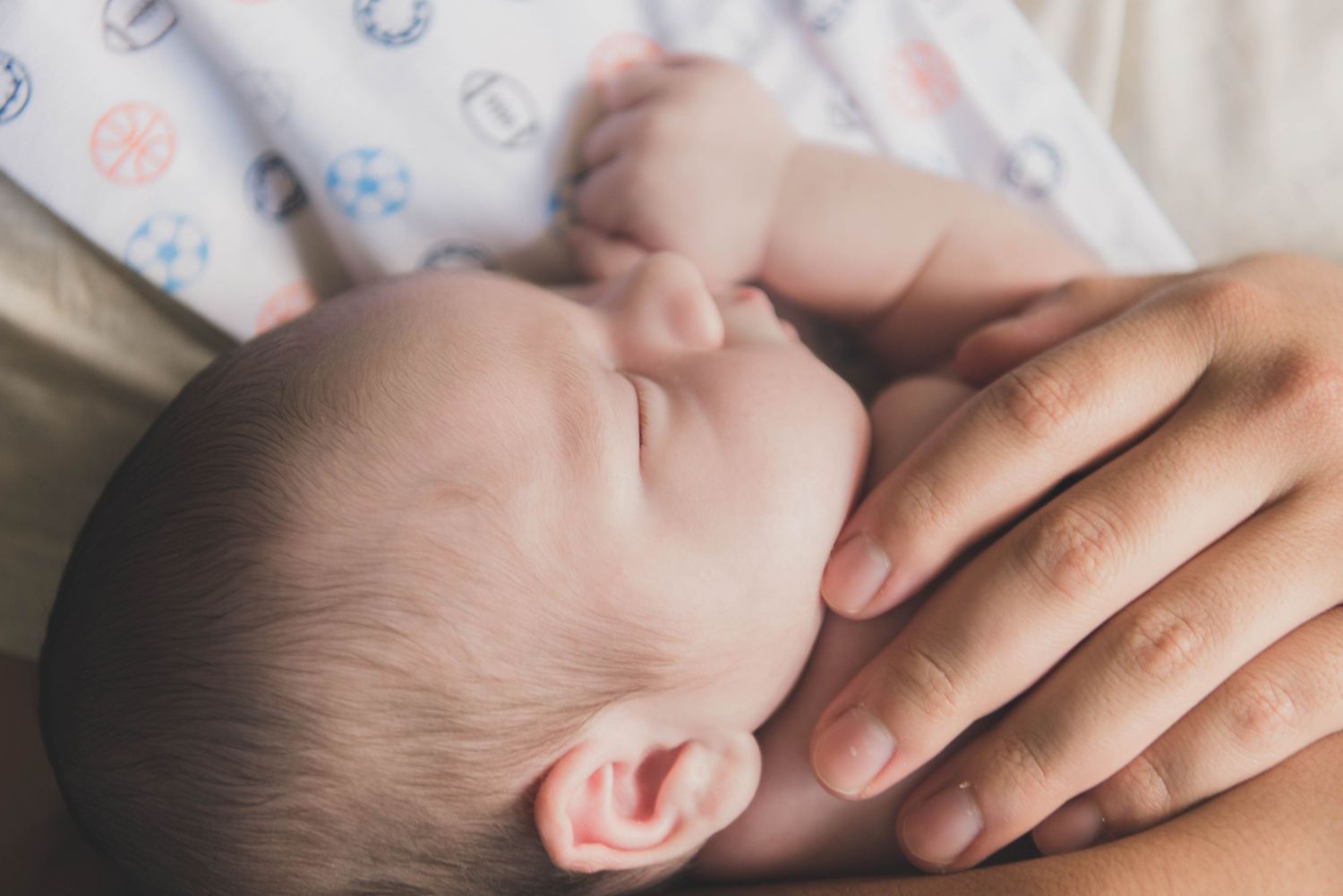 Hands gently massage and apply pressure to a baby's head and face during an infant massage session.