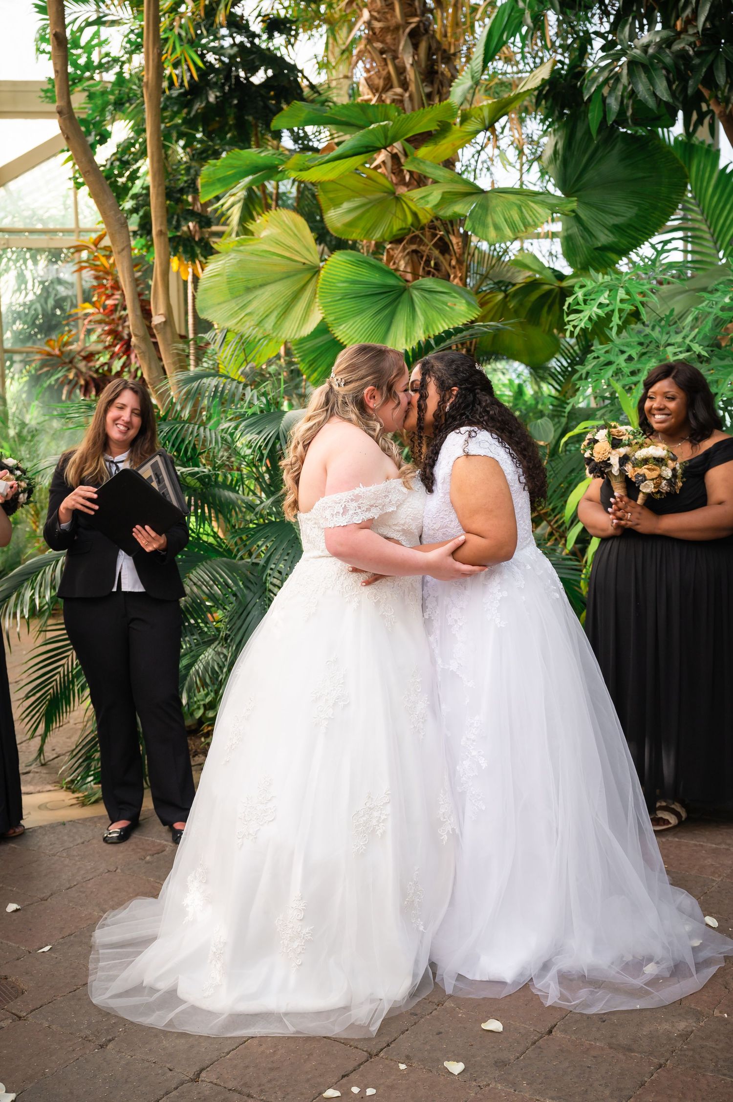 Wedding couple sharing an intimate moment during their ceremony in a greenhouse setting.