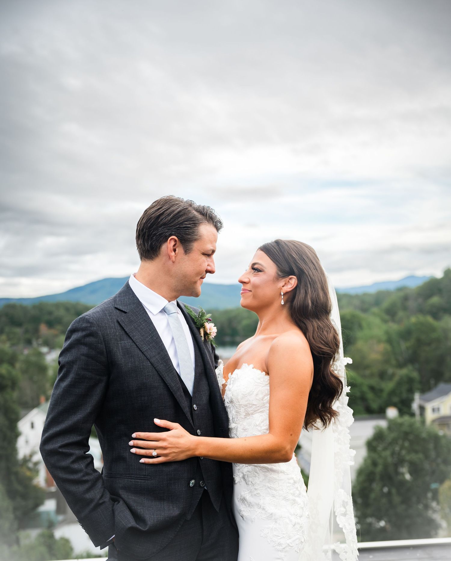 A bride and groom share an intimate moment together on an overlook with scenic rolling hills in the background.