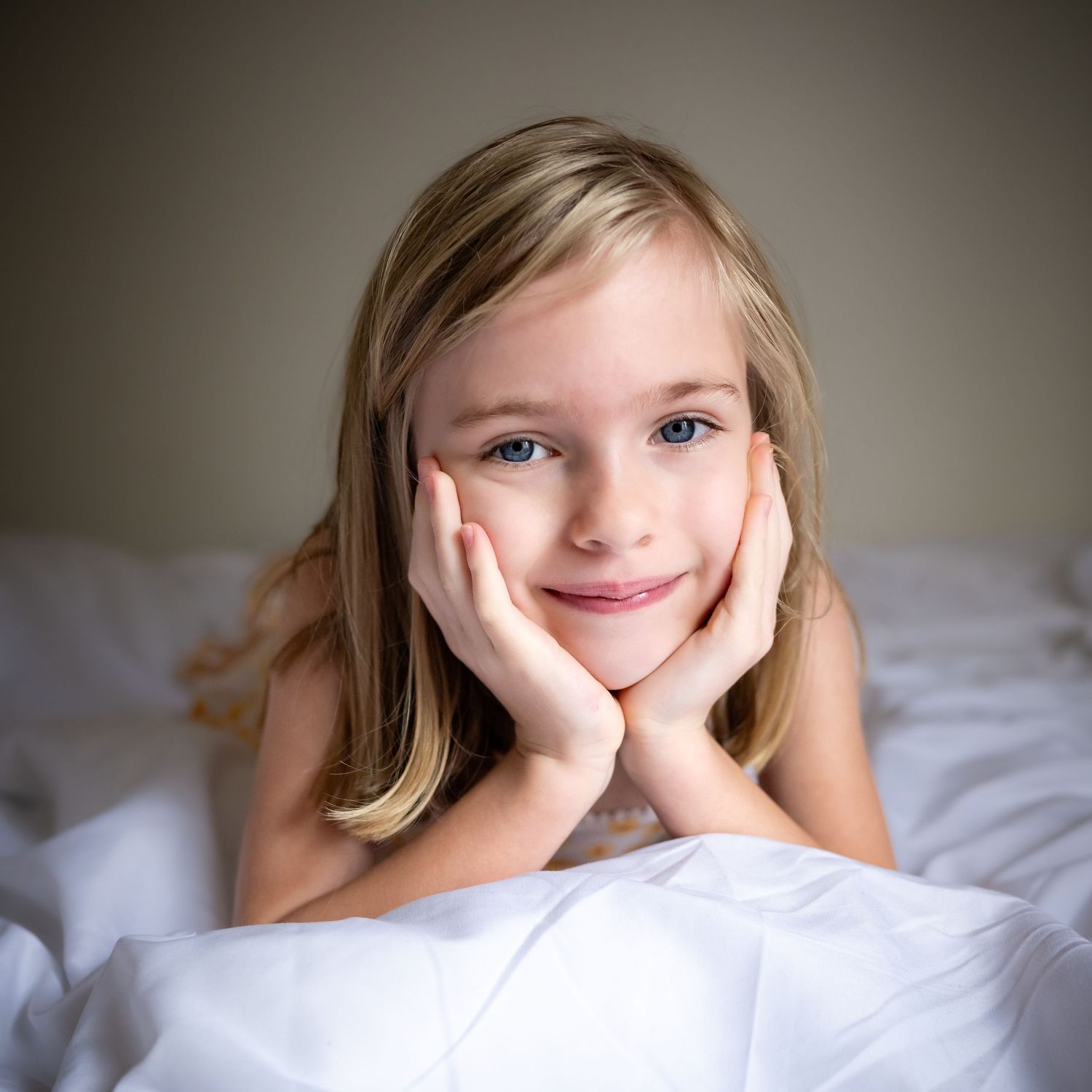 A series of dreamy portrait shots showing a person with blonde hair lying on white bedding in soft natural light.