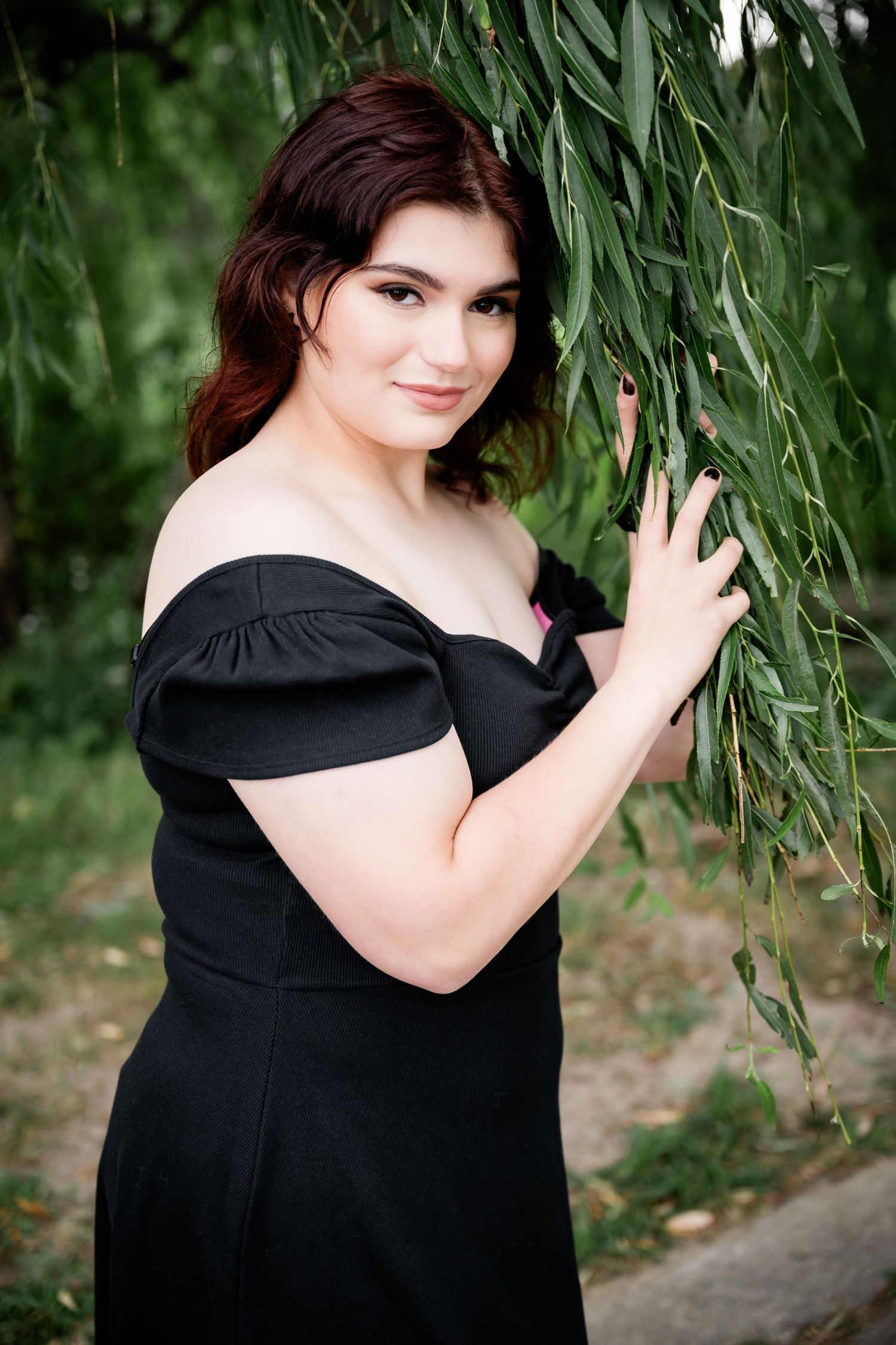 Beautiful outdoor portrait with flowing willow leaves creating a romantic natural backdrop.