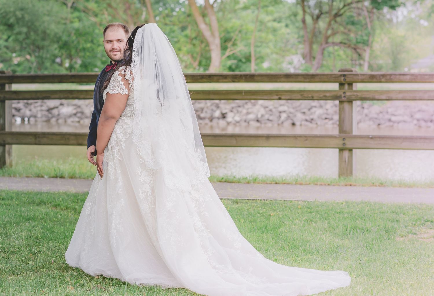 A romantic outdoor wedding portrait with flowing veil and natural scenery.