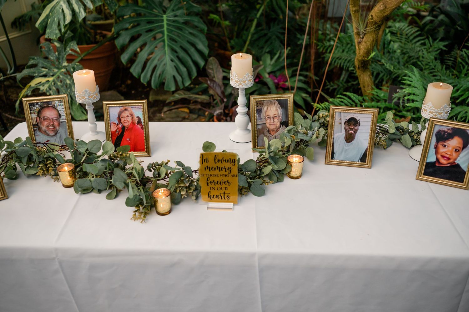Memorial table with candles, photos and greenery garland at wedding reception.