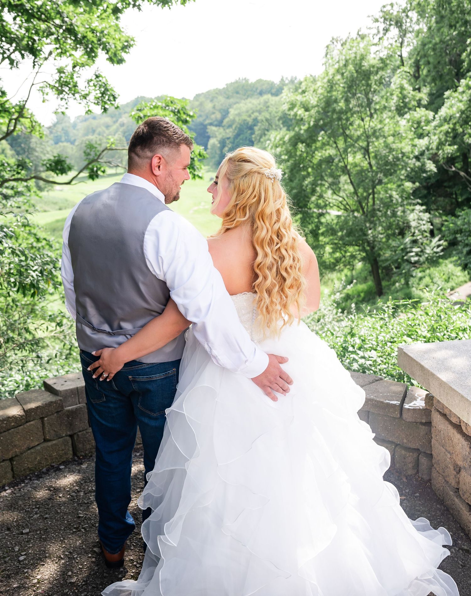 Couple in wedding attire share intimate moment overlooking scenic valley.