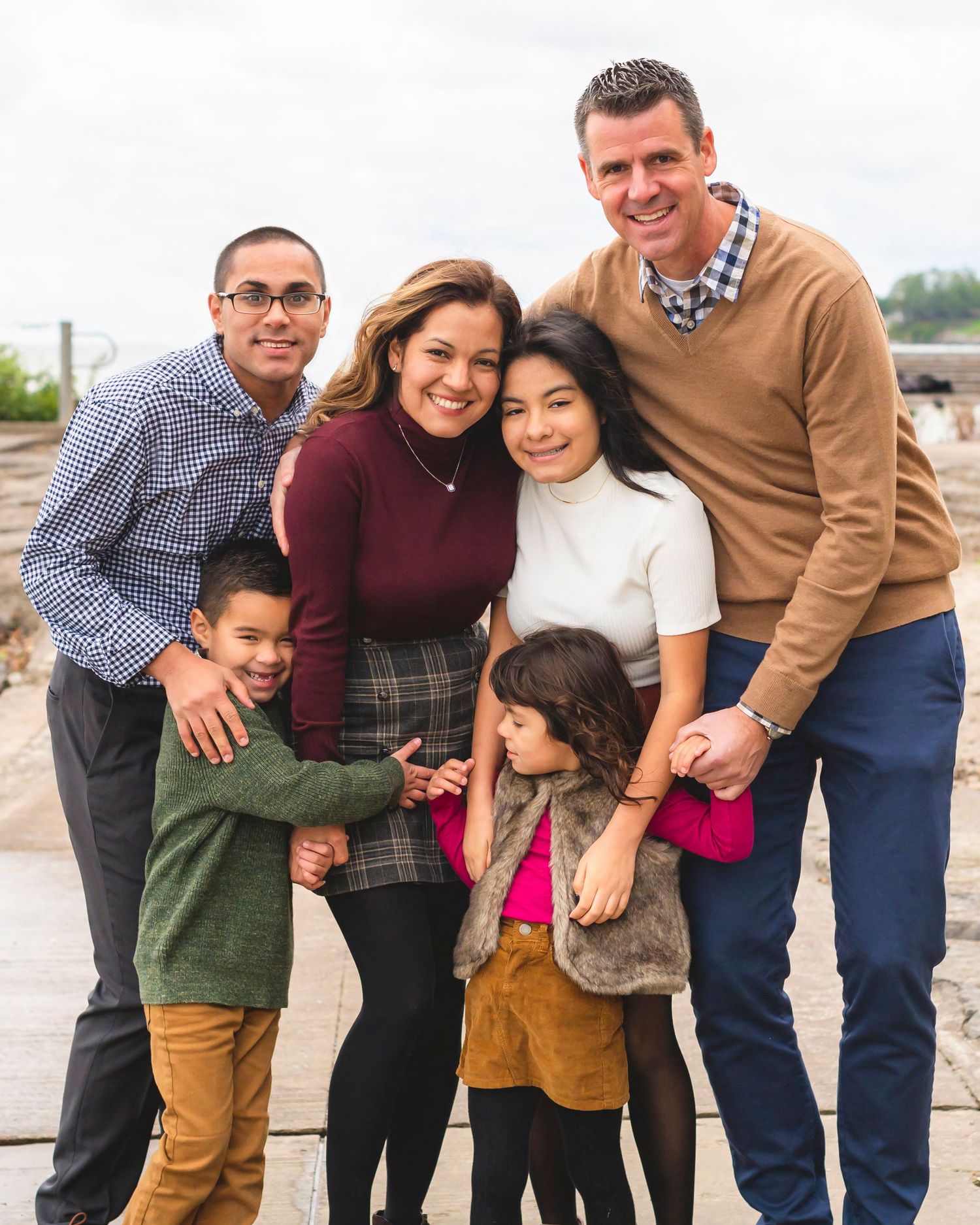 A large multi-generational family poses together outdoors in casual winter clothing for a group photo session.