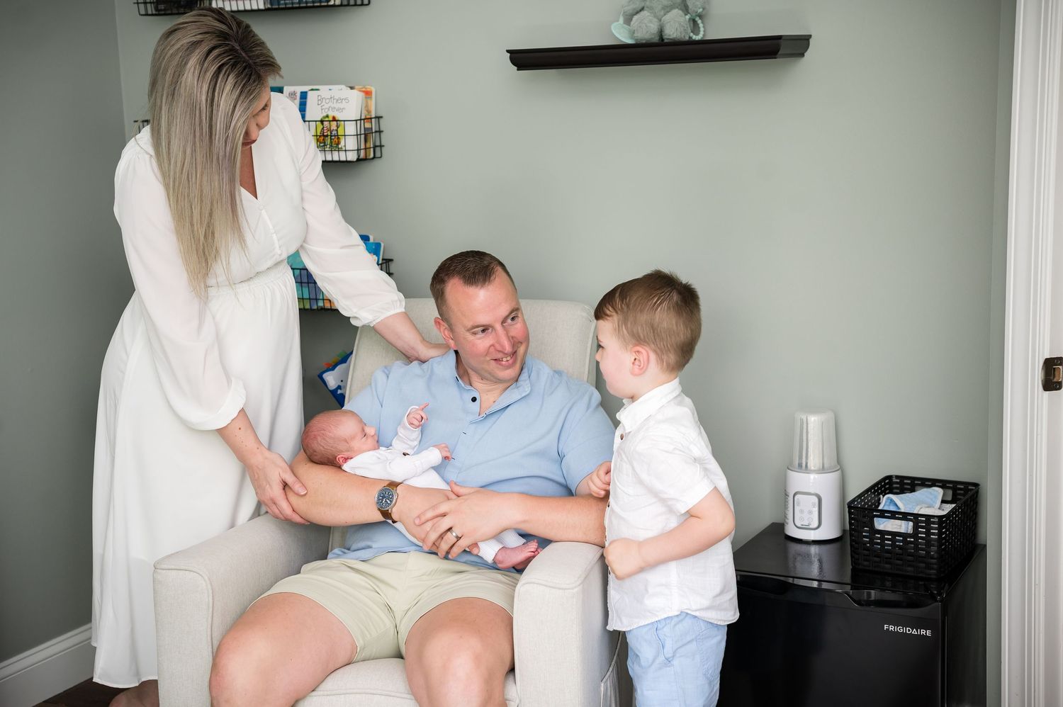 A family shares a tender moment together in a bright white room while sitting on a couch.