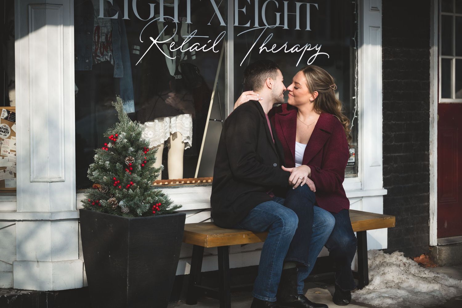 Couple sharing a romantic moment on a bench outside Eight Eight Retail Therapy shop decorated for Christmas.