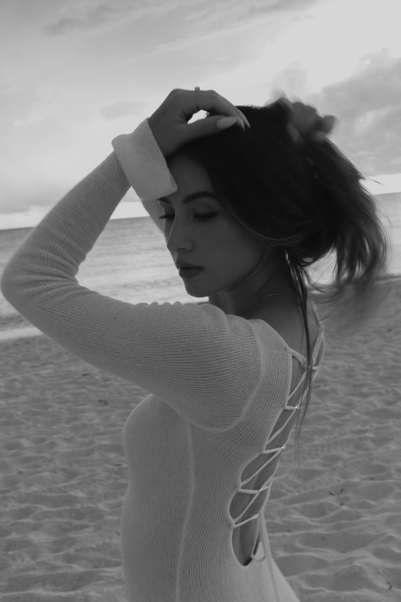 Woman playing with her hair and looking back at the beach in naples Florida