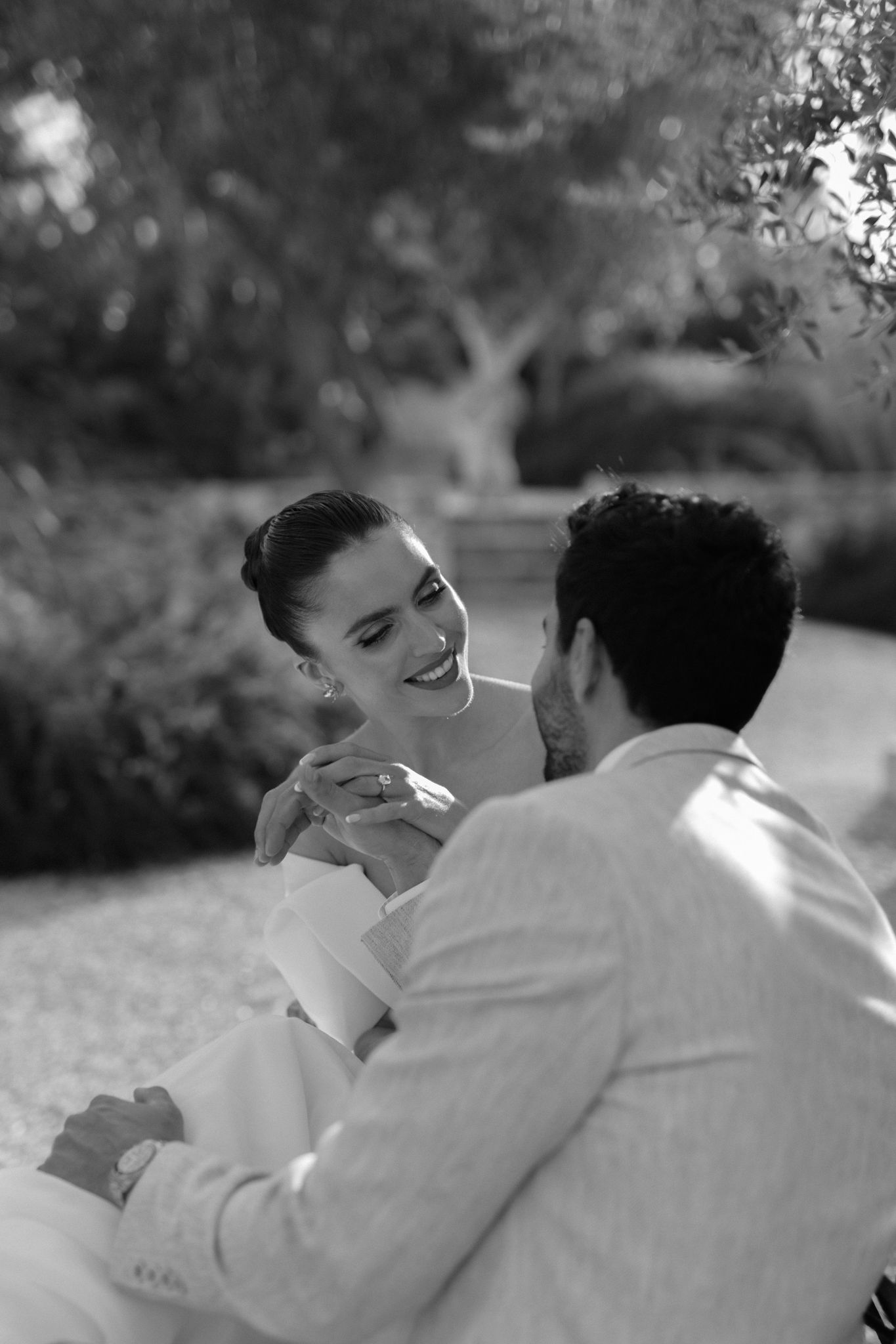 black and white photo of Bride looking at groom lovingly while playing with each other's hands