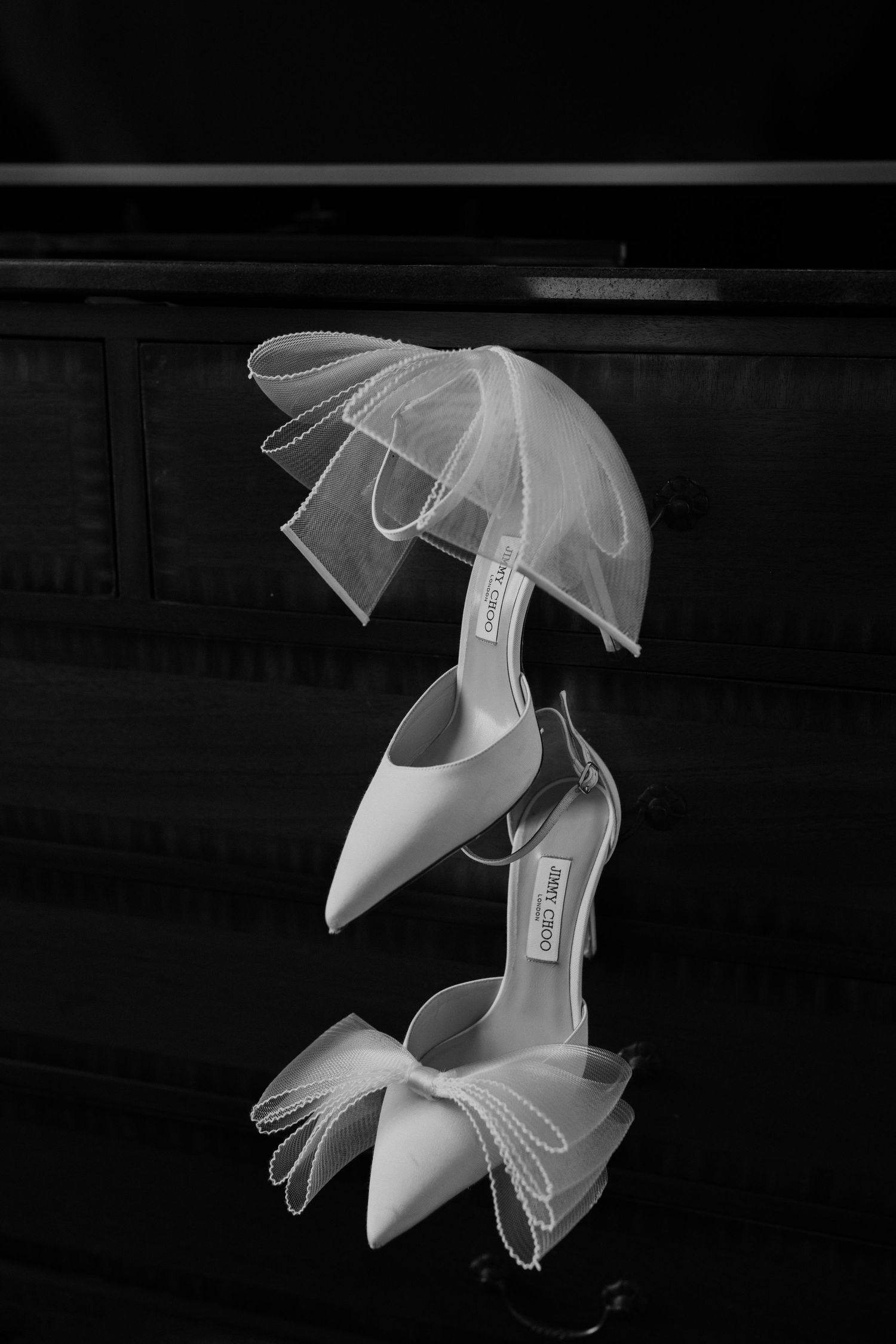 Jimmy Choo wedding shoes hanging from dresser artistically