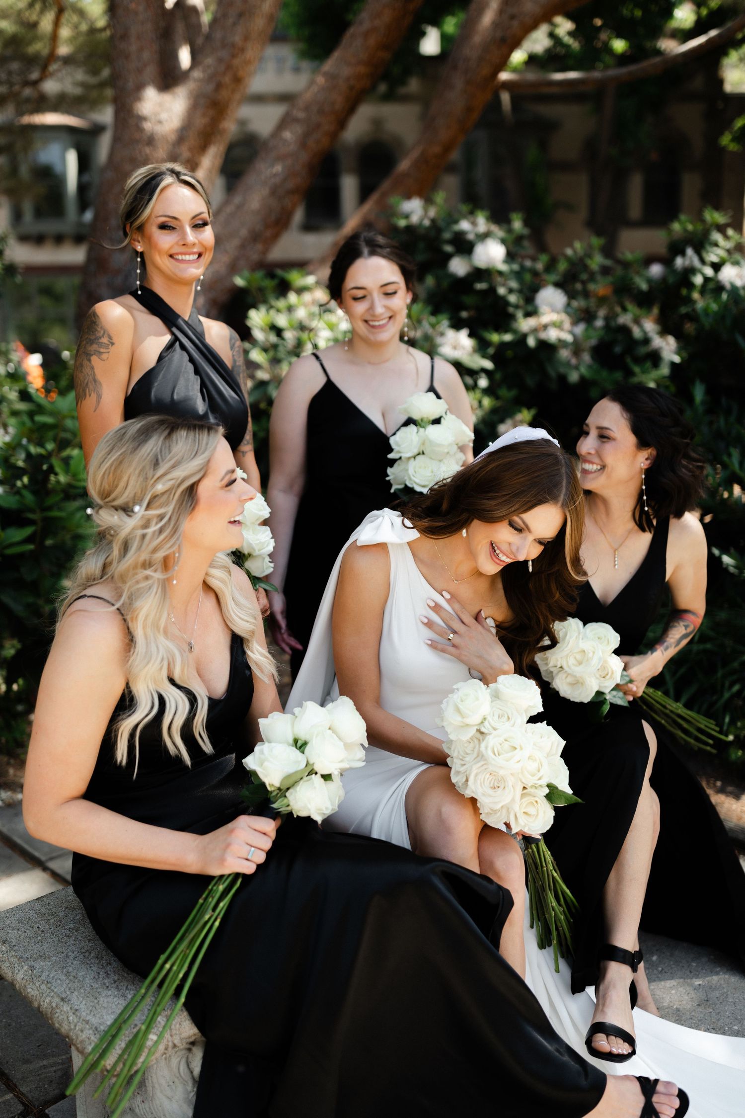 bridesmaids laughing while holding white rose bouquet arrangements