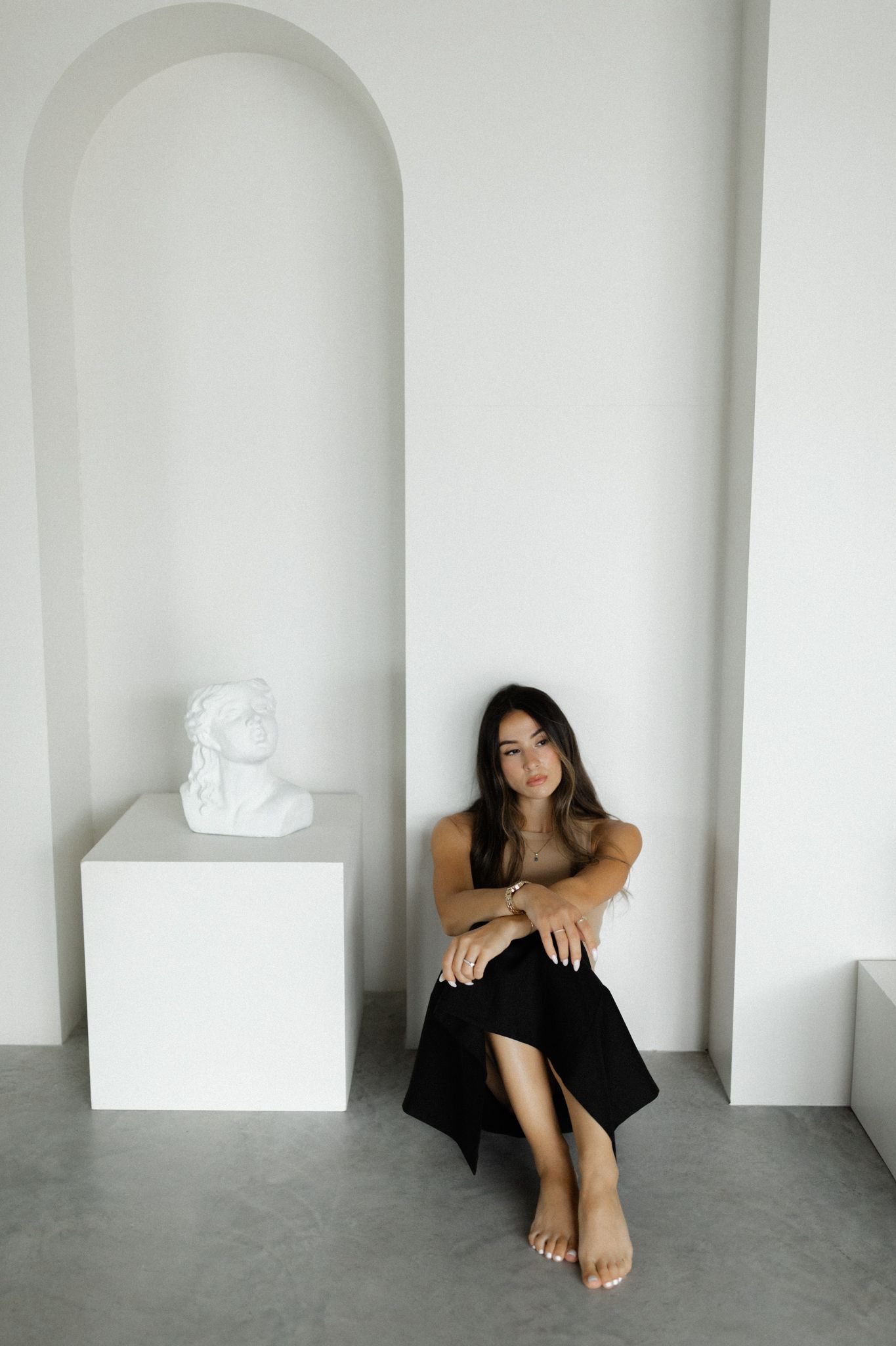 Woman sitting leaning against a wall in a studio