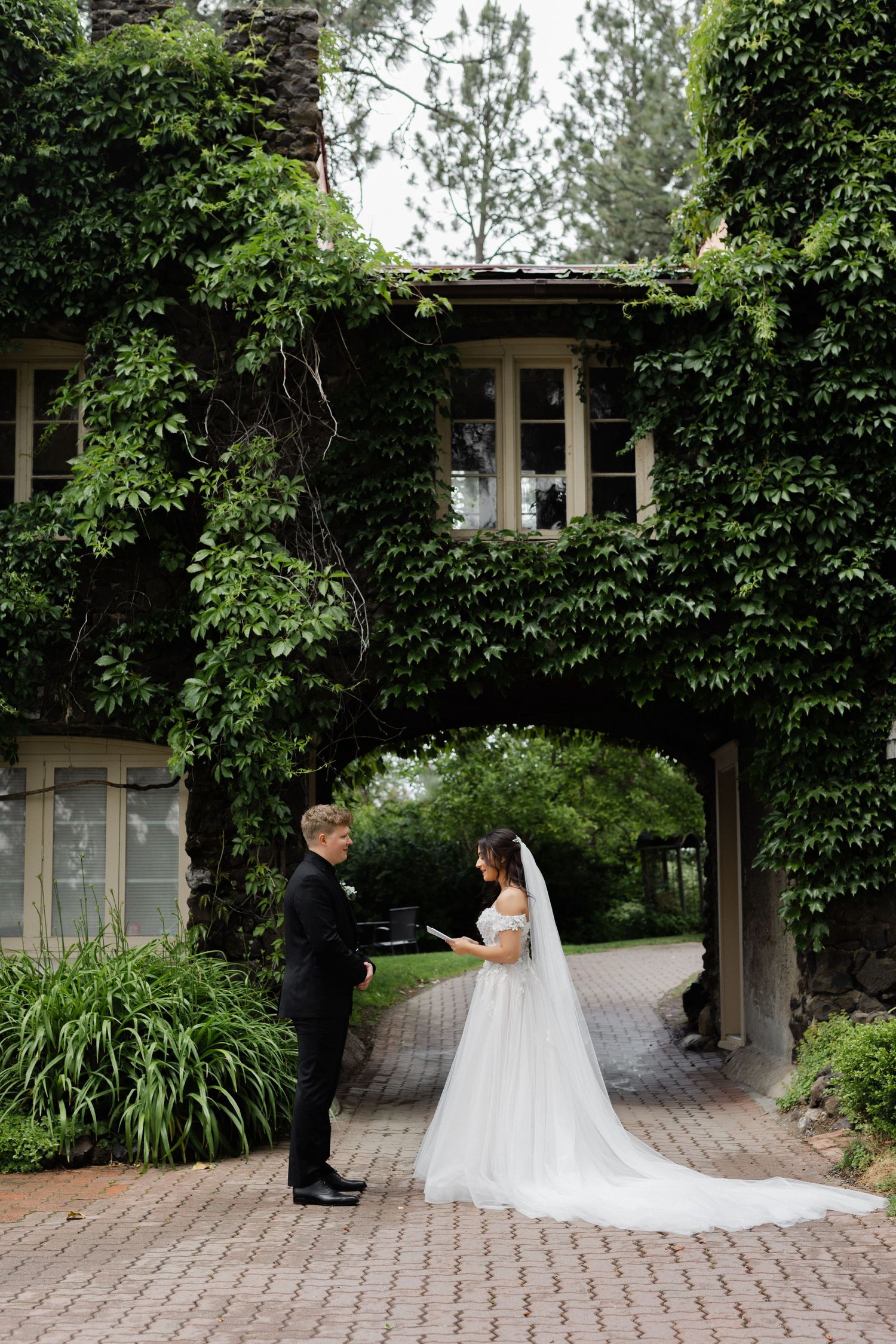 bride and groom reading vows under a vine arches bridge at arbor crest wedding venue
