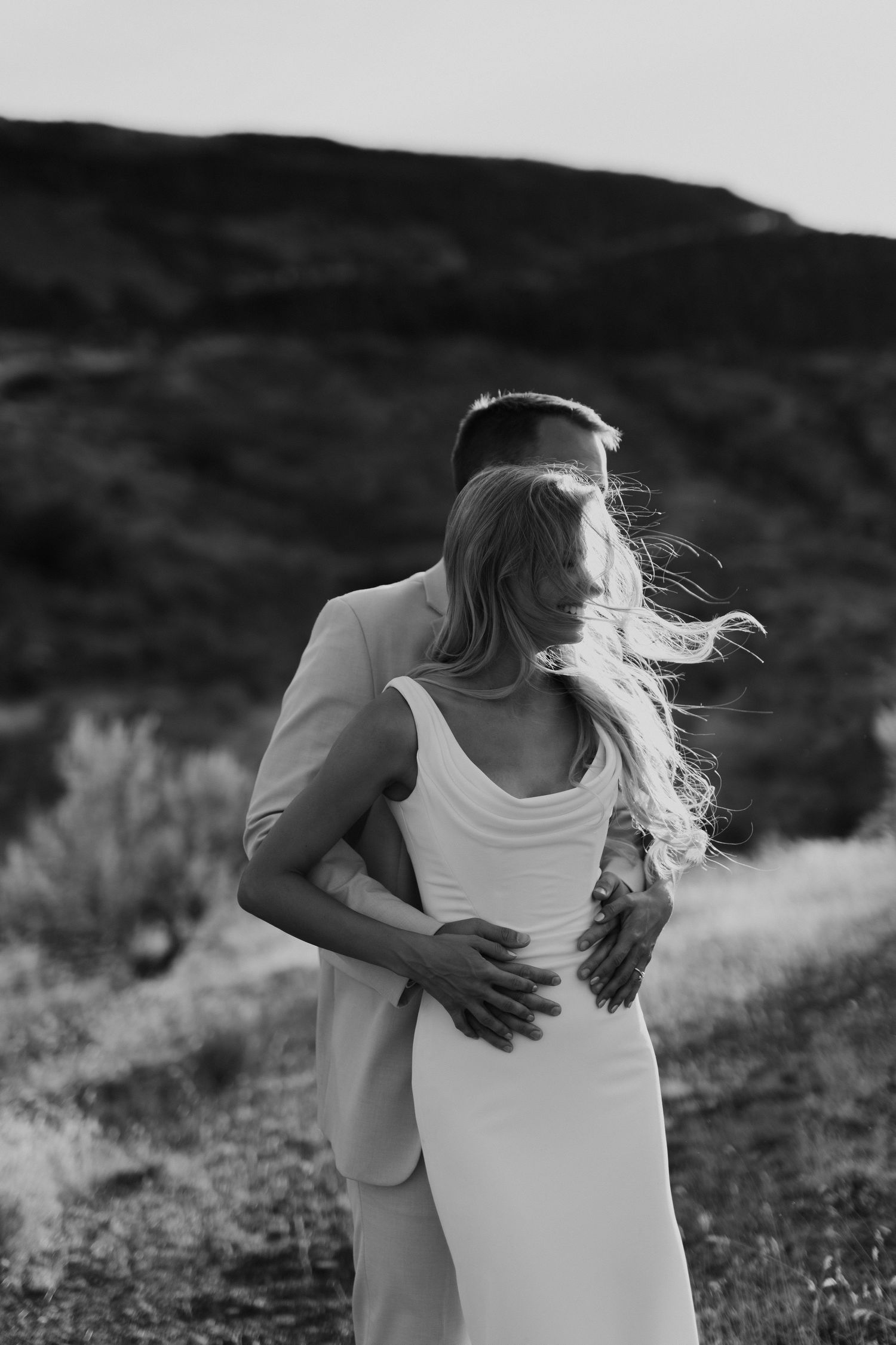 groom holding his bride as the wind is blowing her hair