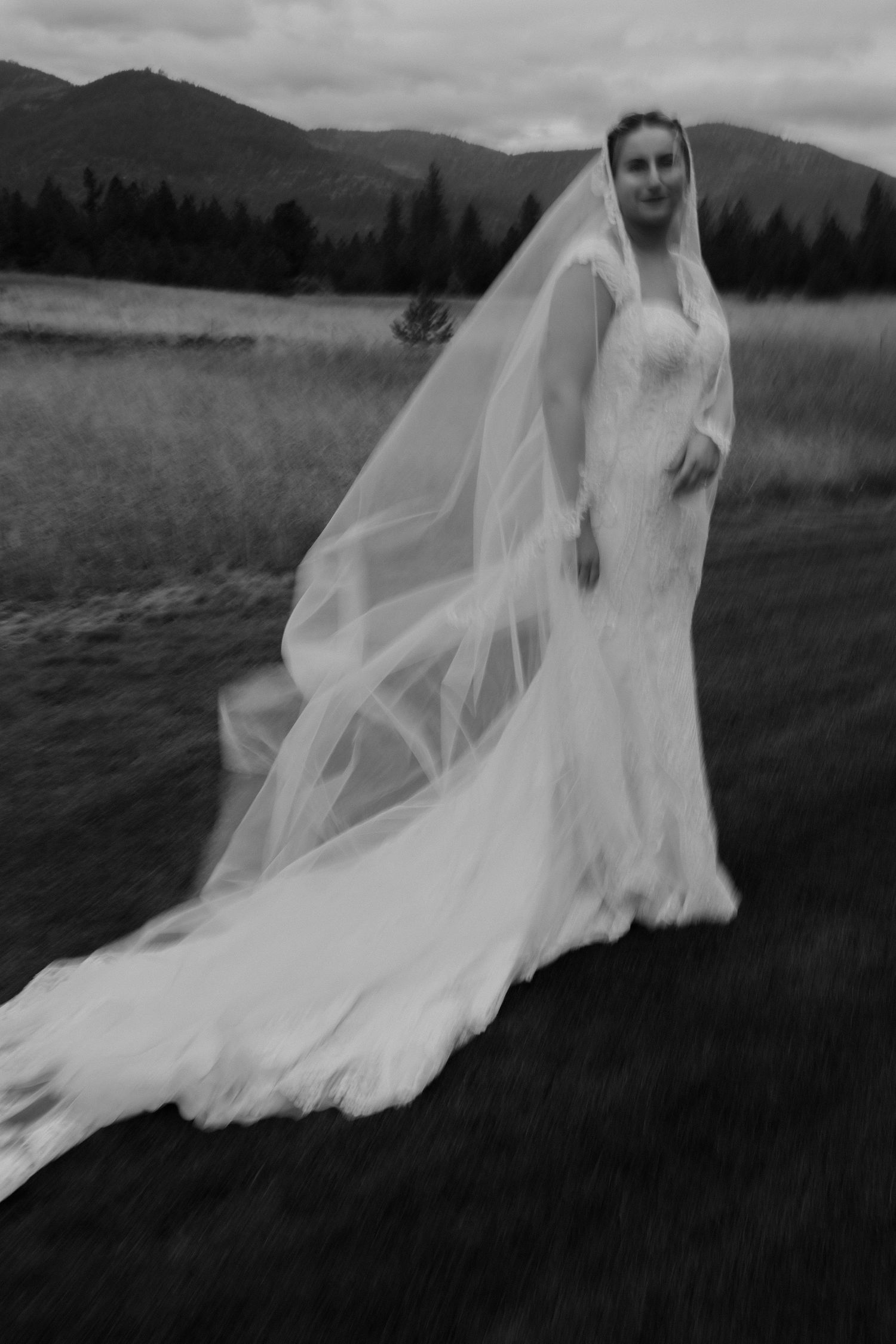 Epic slow shutter drag of bride in her veil blowing in the wind, mountain background