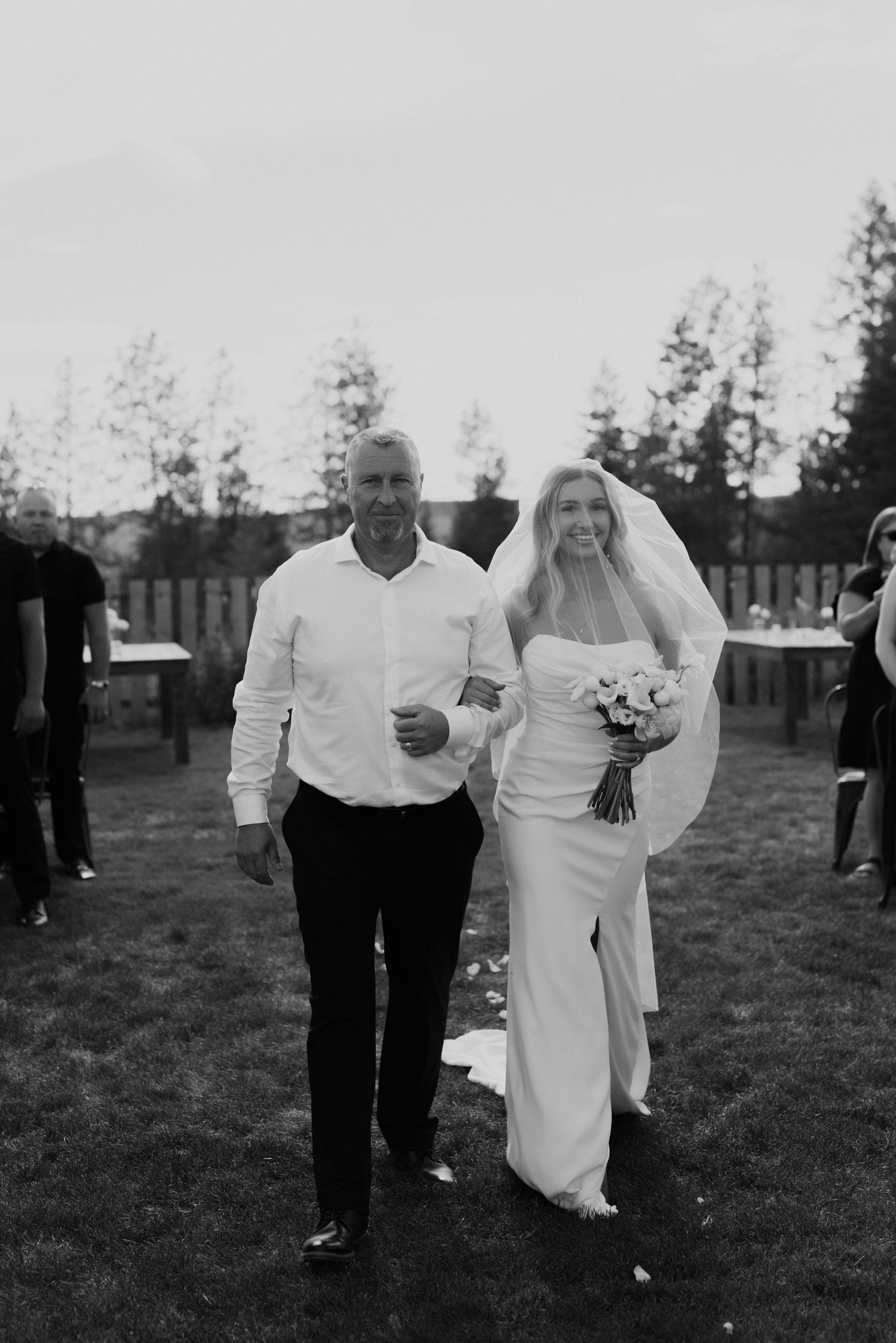 bride walking down the aisle with her veil covered with her father