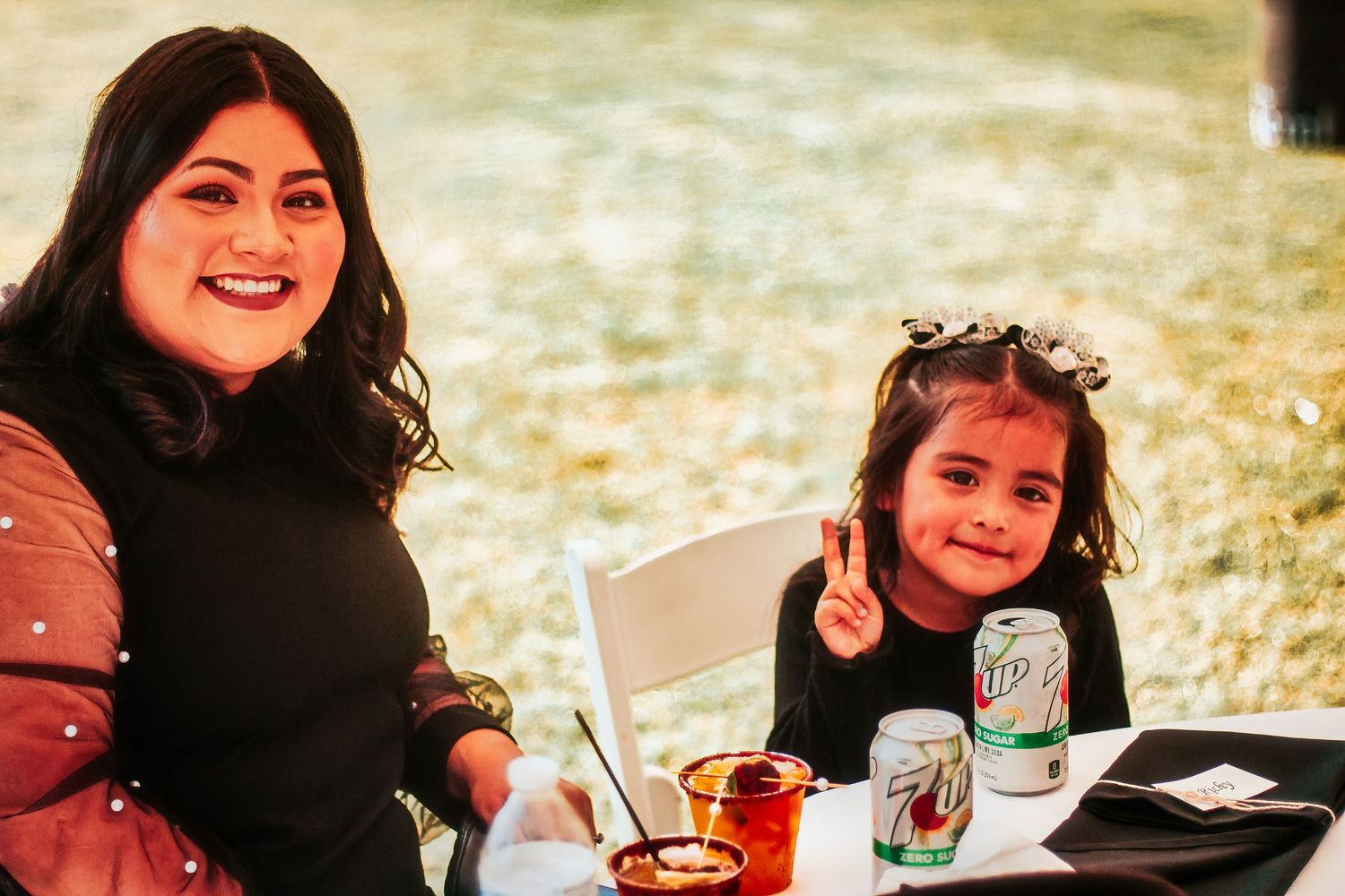 Two people enjoying an outdoor picnic with drinks and snacks on a sunny day.