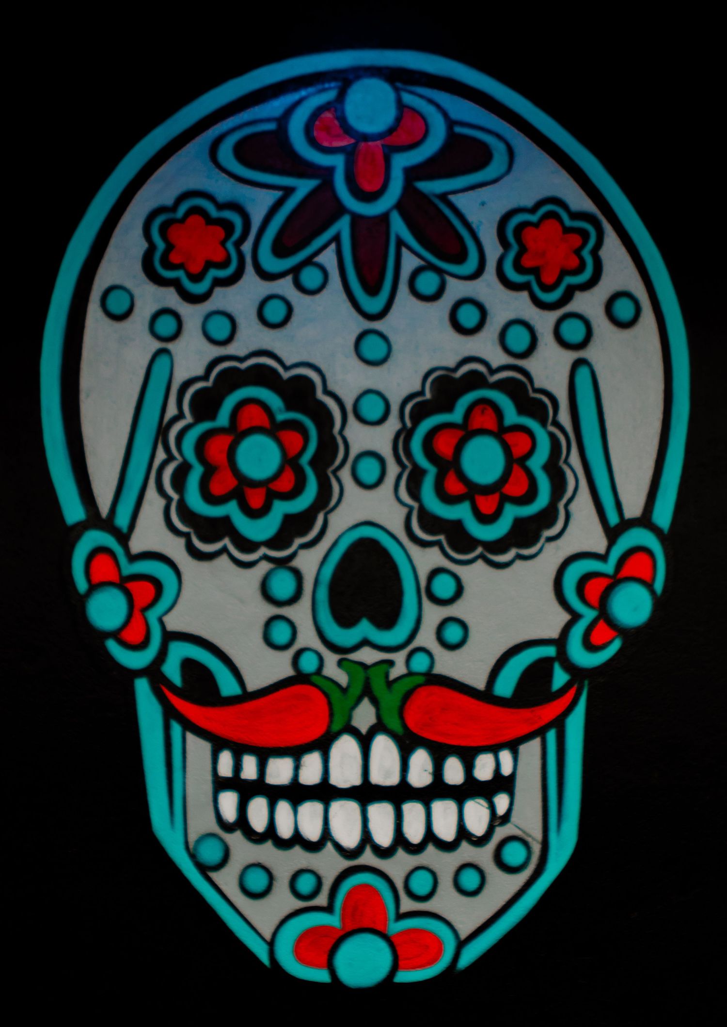 A traditional Mexican sugar skull design featuring turquoise, red and white decorative floral patterns on a dark background.