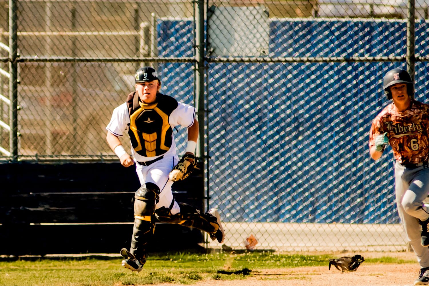 Baseball player in yellow and black uniform gets ready to field a play at home plate during a game.
