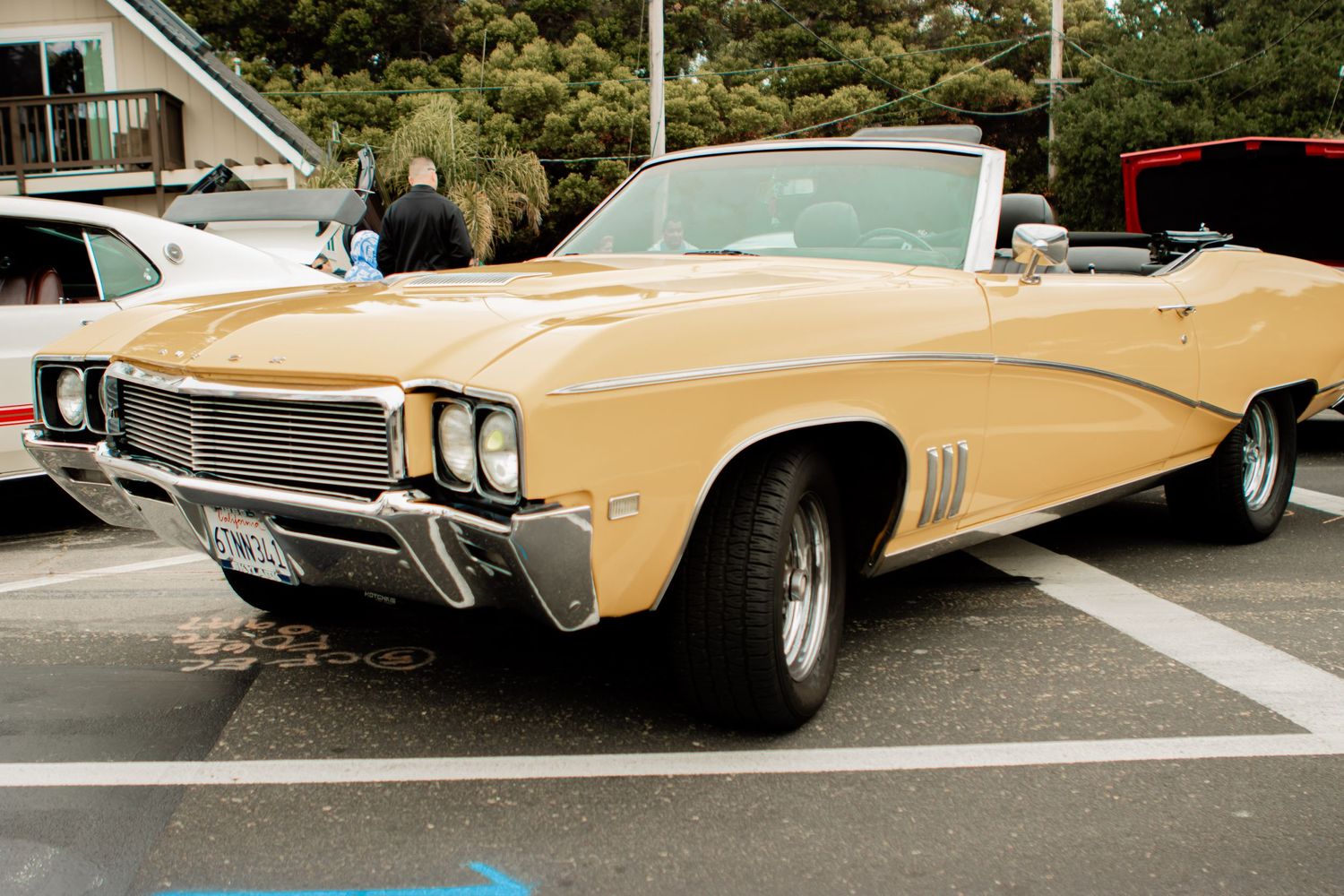 A classic cream-colored Buick convertible with chrome trim parked in a parking lot.