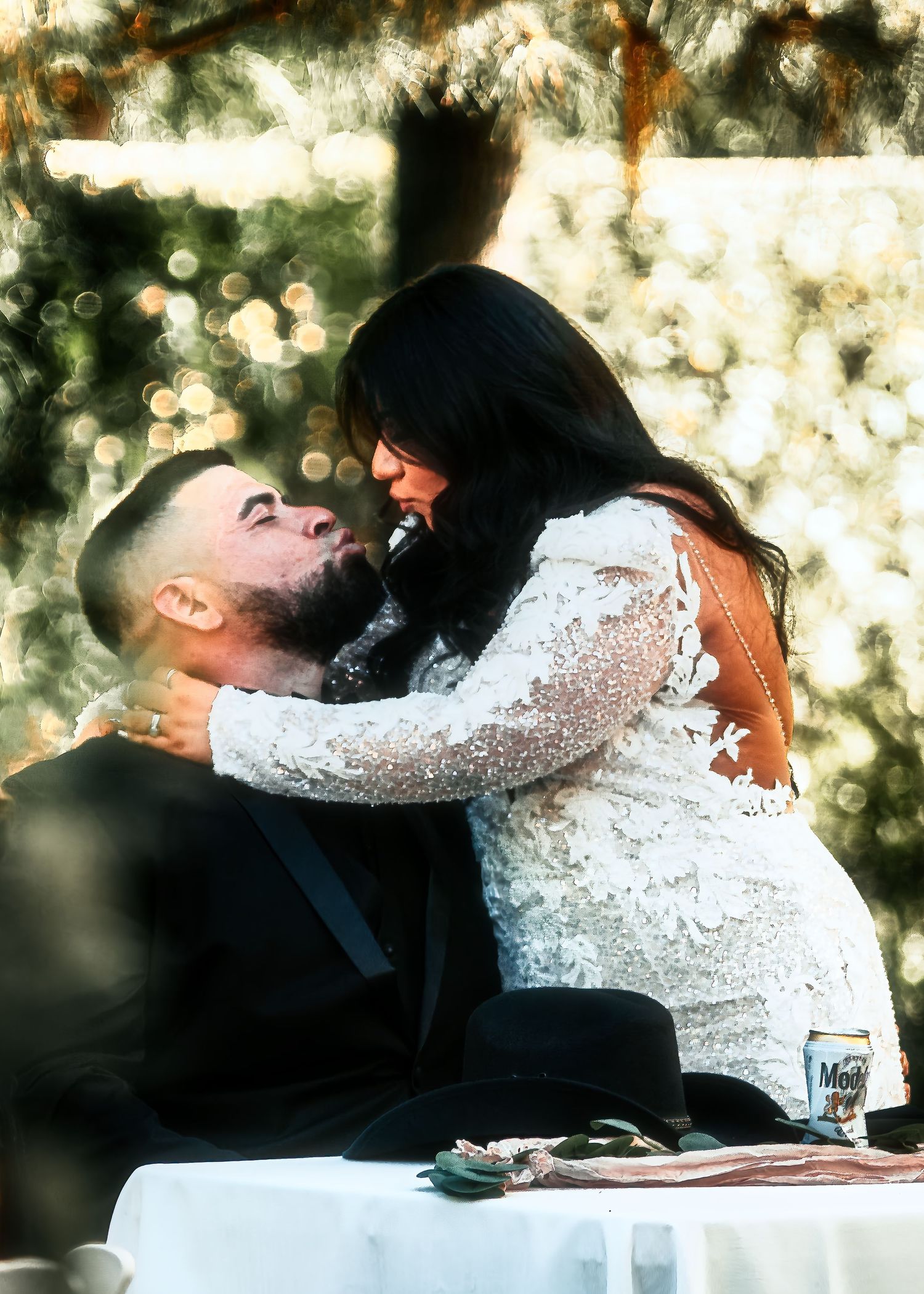 A romantic moment between a couple in formal attire embracing outdoors with bokeh lighting effects in the background.